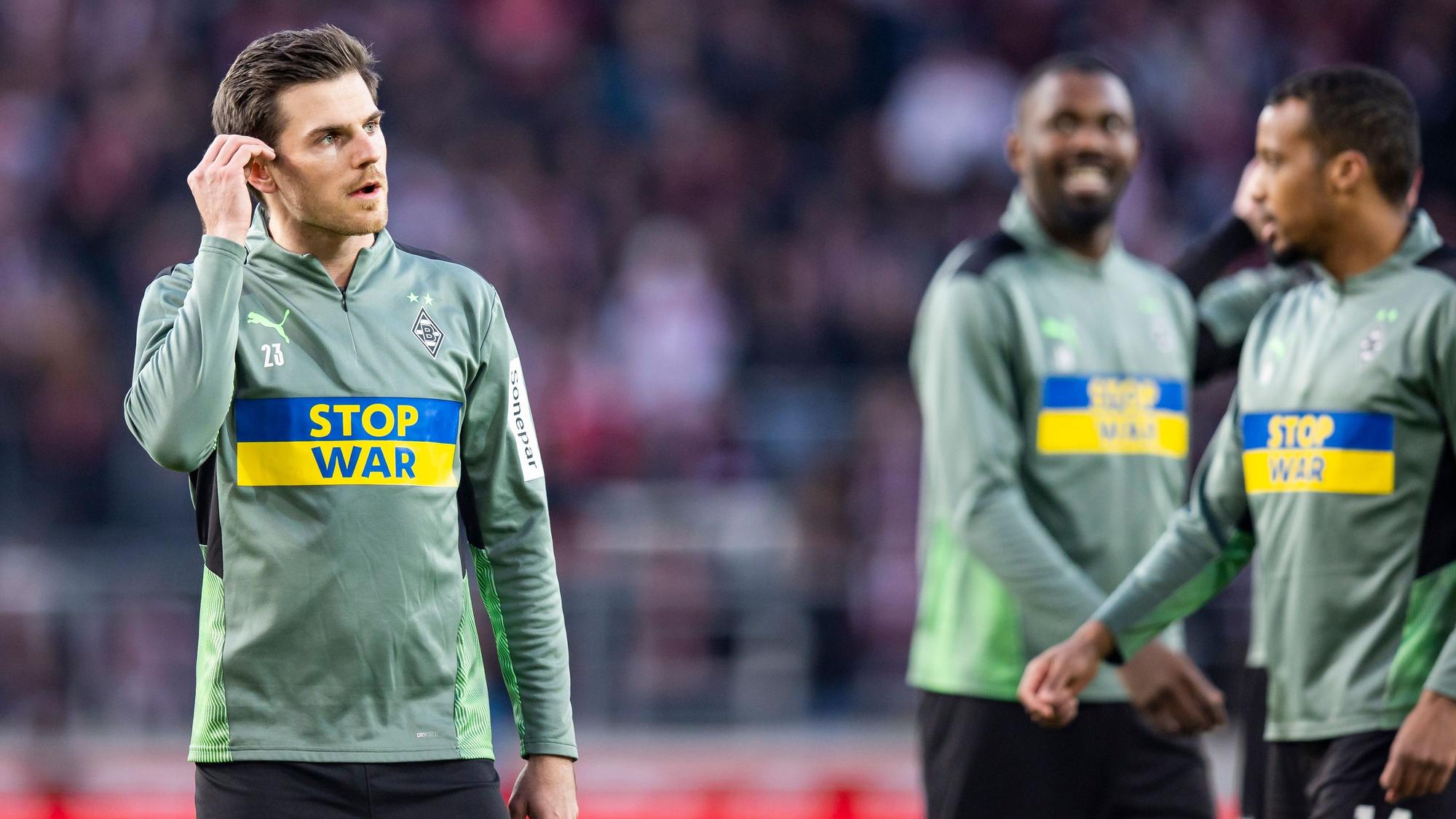 Gladbach-Profi Jonas Hofmann vor der Bundesliga-Partie der Borussia beim VfB Stuttgart am 6. März 2022. Hofmann steht beim Aufwärmen mit Sonder-Aufwärmtrikot und der Aufschrift «Stop War» und den Farben der Ukraine auf dem Platz.