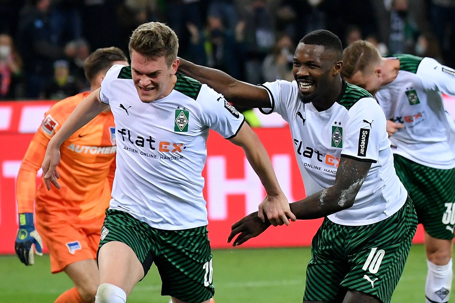 Borussia-Mönchengladbach-Stürmer Marcus Thuram (r.) steht erneut im Fokus einiger europäischer Top-Klubs. Hier bejubelt Thuram zusammen mit Matthias Ginter (l.) den Treffer zum 2:0 gegen Hertha BSC im Borussia-Park (12. März 2022). Marcus Thuram läuft Matthias Ginter lächelnd hinterher und versucht ihn zu greifen.