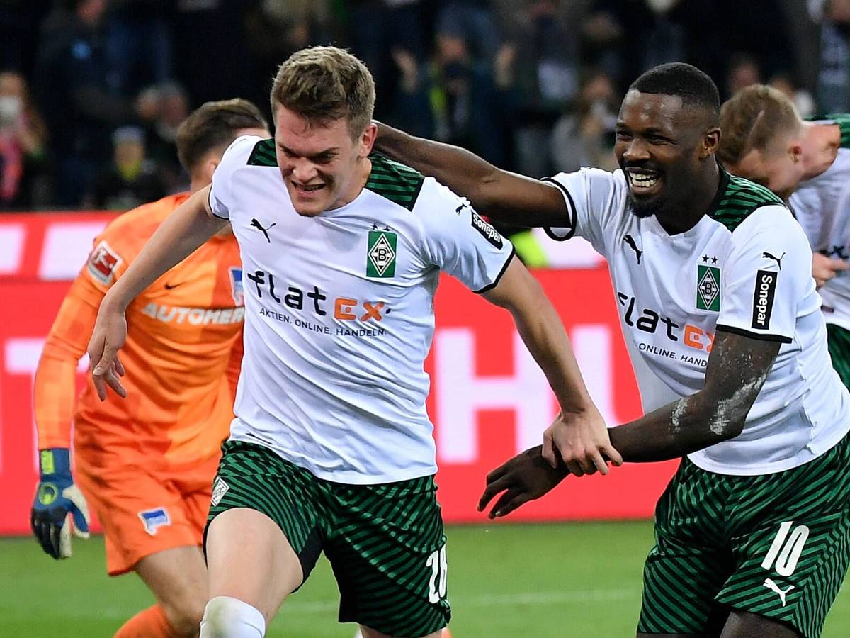 Borussia-Mönchengladbach-Stürmer Marcus Thuram (r.) steht erneut im Fokus einiger europäischer Top-Klubs. Hier bejubelt Thuram zusammen mit Matthias Ginter (l.) den Treffer zum 2:0 gegen Hertha BSC im Borussia-Park (12. März 2022). Marcus Thuram läuft Matthias Ginter lächelnd hinterher und versucht ihn zu greifen.