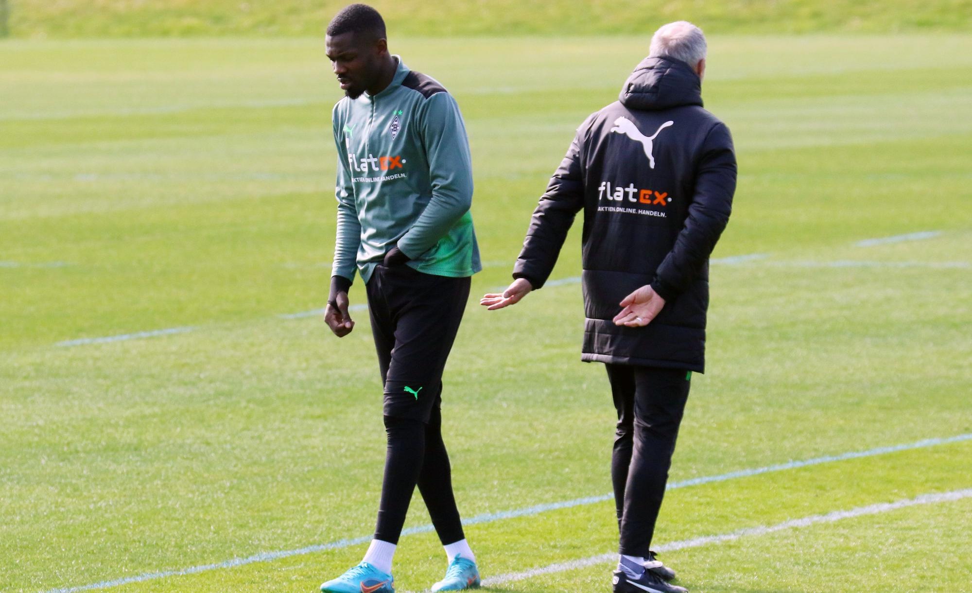 Marcus Thuram (l.) mit Coach Adi Hütter (r.) während einer Trainingseinheit im Borussia-Park am 30. März 2022. Thuram greift sich in die Hose.