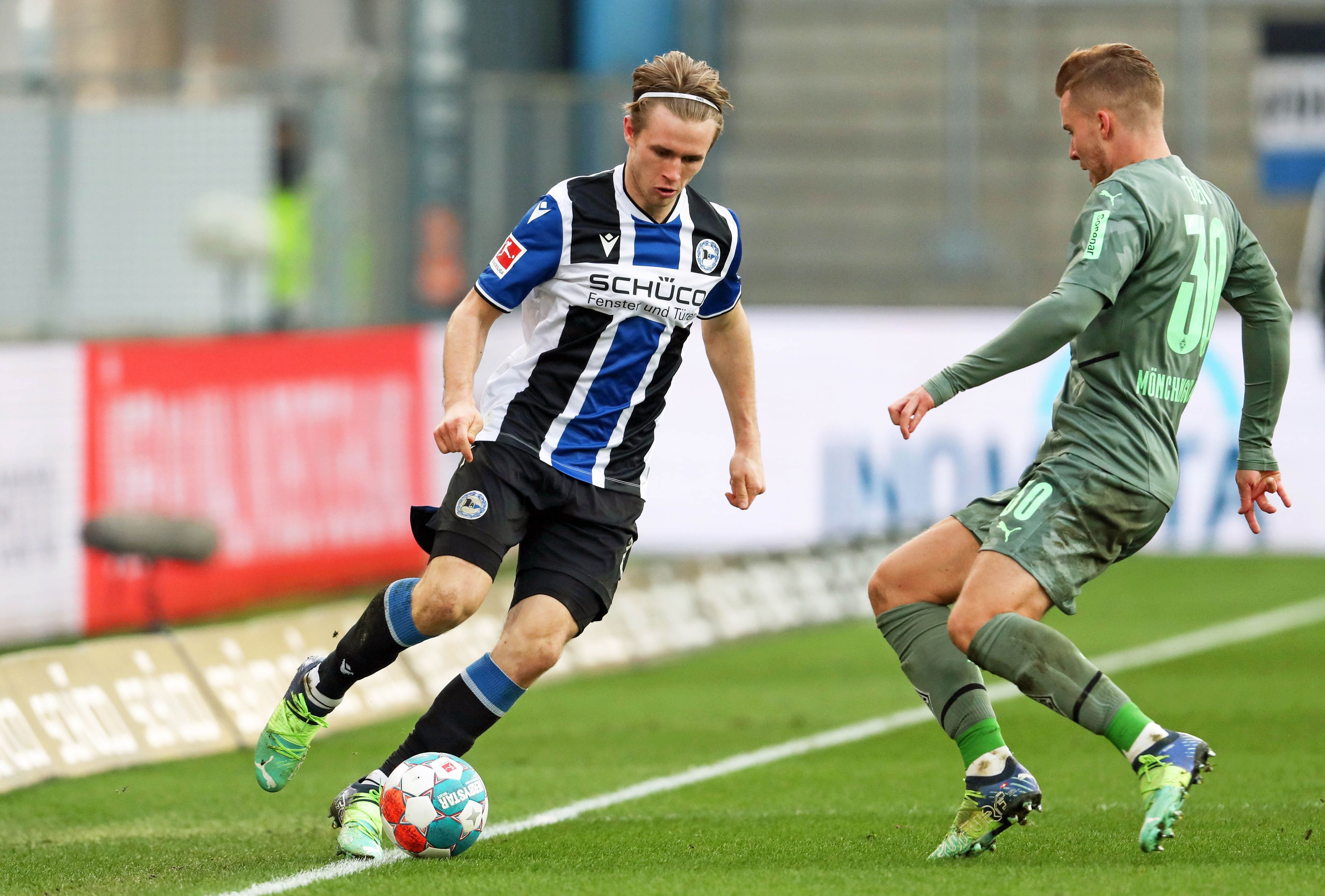 Patrick Wimmer (l.) von Arminia Bielefeld im Zweikampf mit Nico Elvedi (r.) von Borussia Mönchengladbach im Bundesligaspiel am 5. Februar 2022 auf der Alm. Wimmer hat den Ball am Fuß.