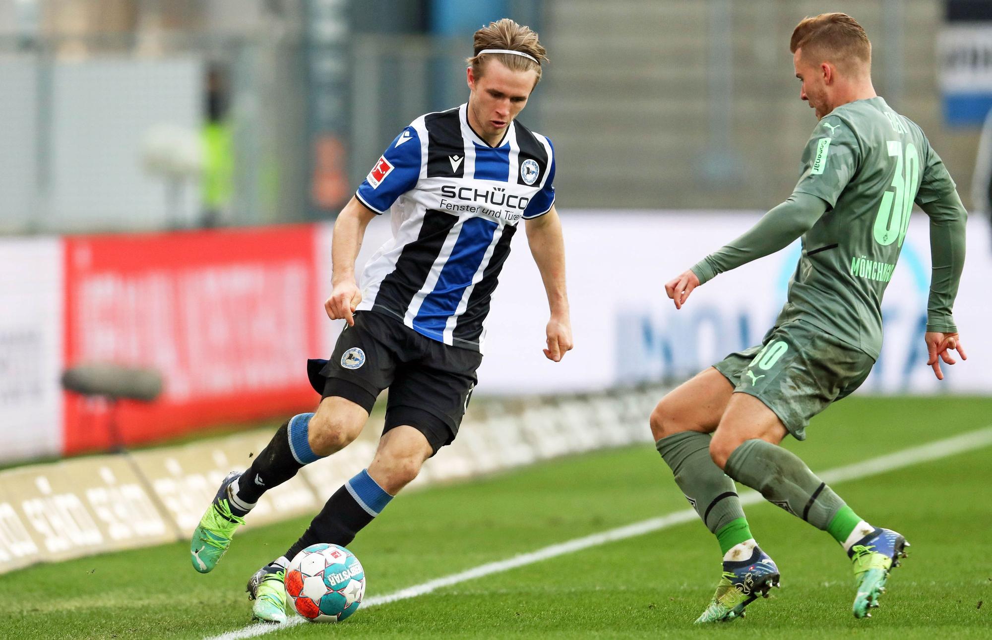 Patrick Wimmer (l.) von Arminia Bielefeld im Zweikampf mit Nico Elvedi (r.) von Borussia Mönchengladbach im Bundesligaspiel am 5. Februar 2022 auf der Alm. Wimmer hat den Ball am Fuß.