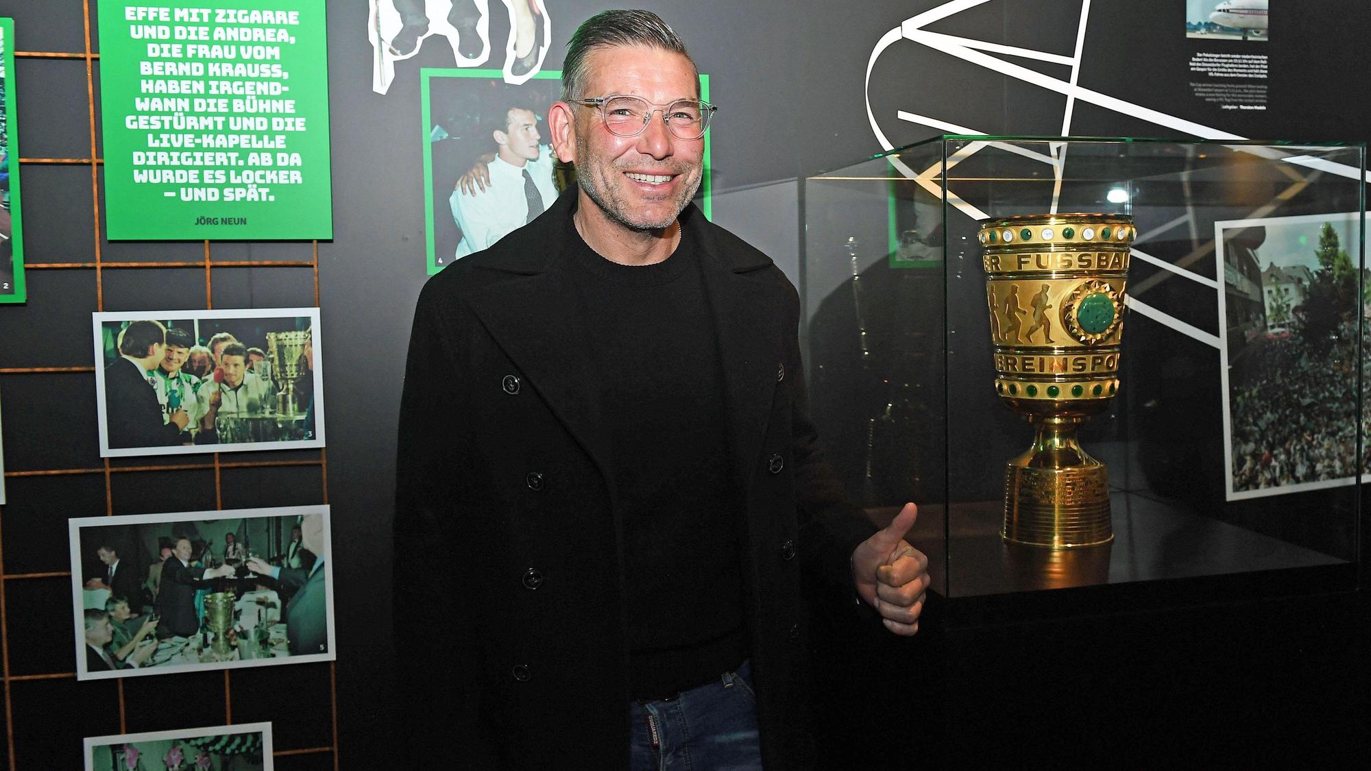 DFB-Pokalsieger und Torhüterlegende von Borussia Mönchengladbach, Uwe Kamps, in der Fohlen-Welt am 3. April 2022. Uwe Kamps steht lächelnd, mit dem linken Daumen nach oben, vor dem DFB-Pokal.