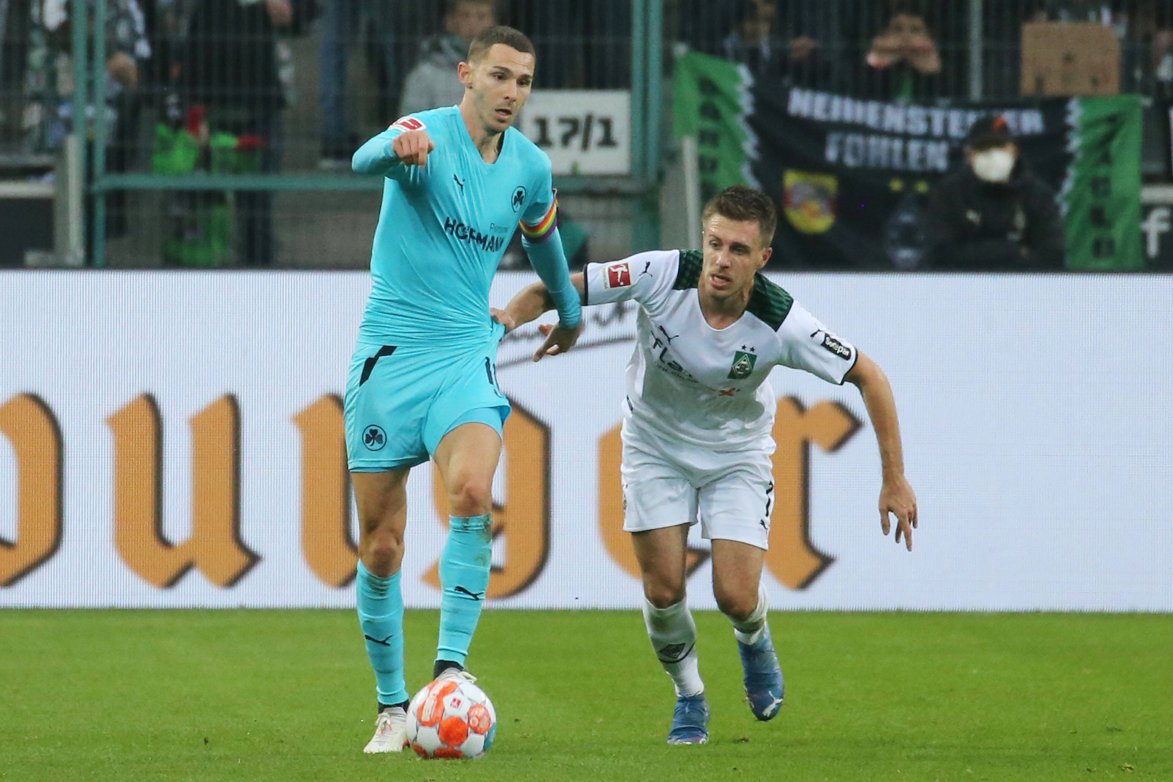 Branimir Hrgota, Ex-Spieler von Borussia Mönchengladbach, im Duell mit Gladbacher-Urgestein Patrick Herrmann in der Partie am 20. November 2021. Hrgota läuft mit dem Ball am Fuß vor Herrmann weg.