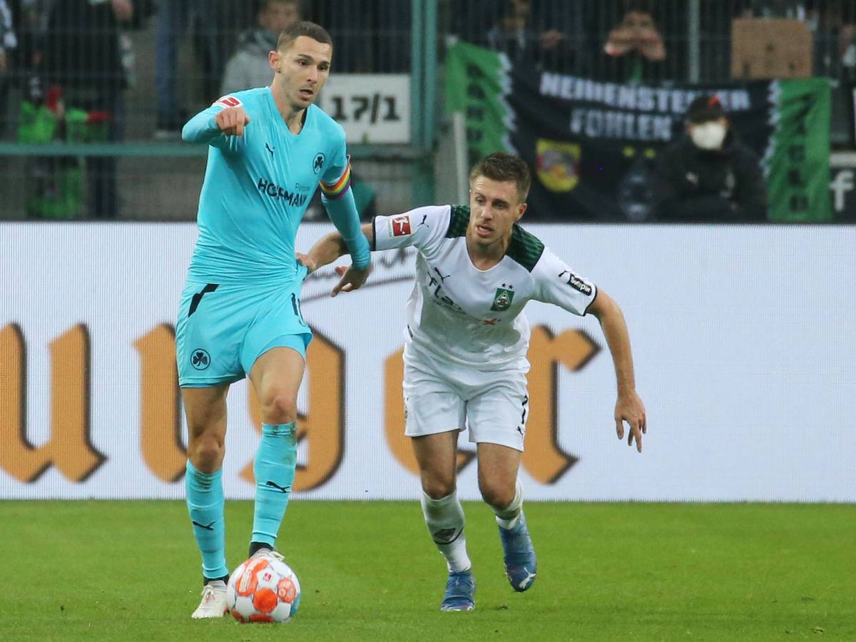 Branimir Hrgota, Ex-Spieler von Borussia Mönchengladbach, im Duell mit Gladbacher-Urgestein Patrick Herrmann in der Partie am 20. November 2021. Hrgota läuft mit dem Ball am Fuß vor Herrmann weg.