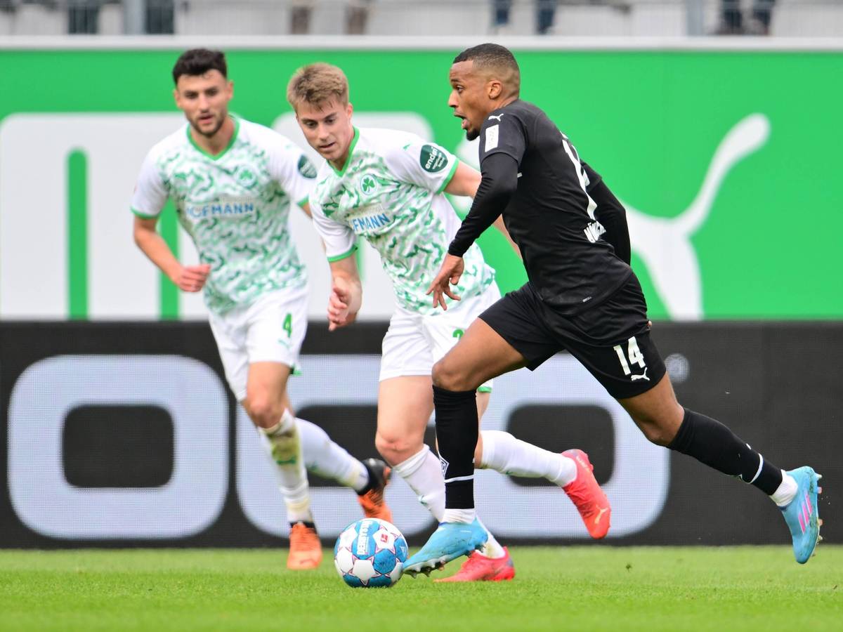 Gladbach-Stürmer Alassane Plea (r.) kann sich in dieser Szene gegen zwei Fürther Spieler durchsetzen (9. April 2022). Plea hat den Ball am Fuß.