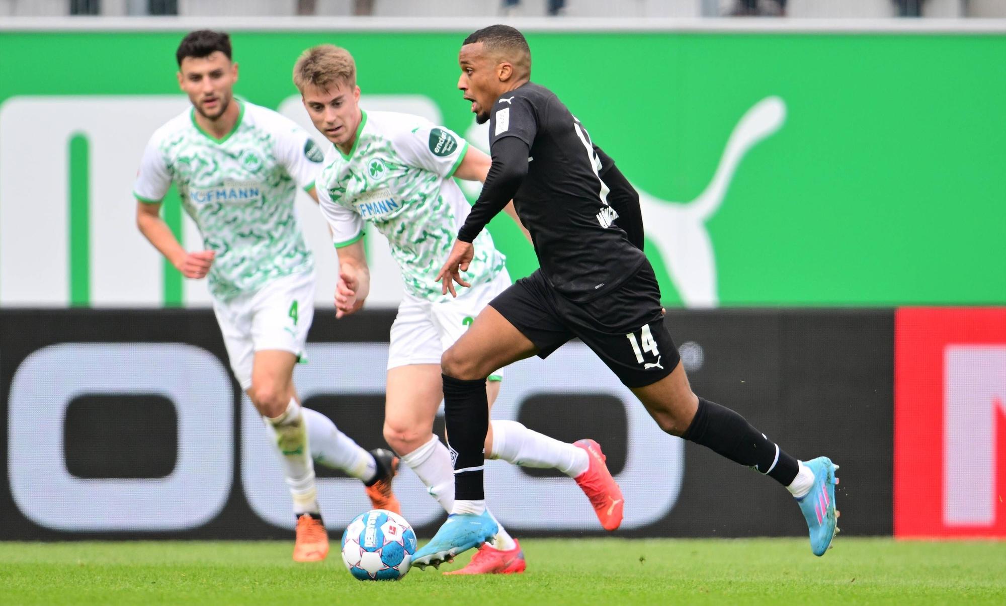 Gladbach-Stürmer Alassane Plea (r.) kann sich in dieser Szene gegen zwei Fürther Spieler durchsetzen (9. April 2022). Plea hat den Ball am Fuß.