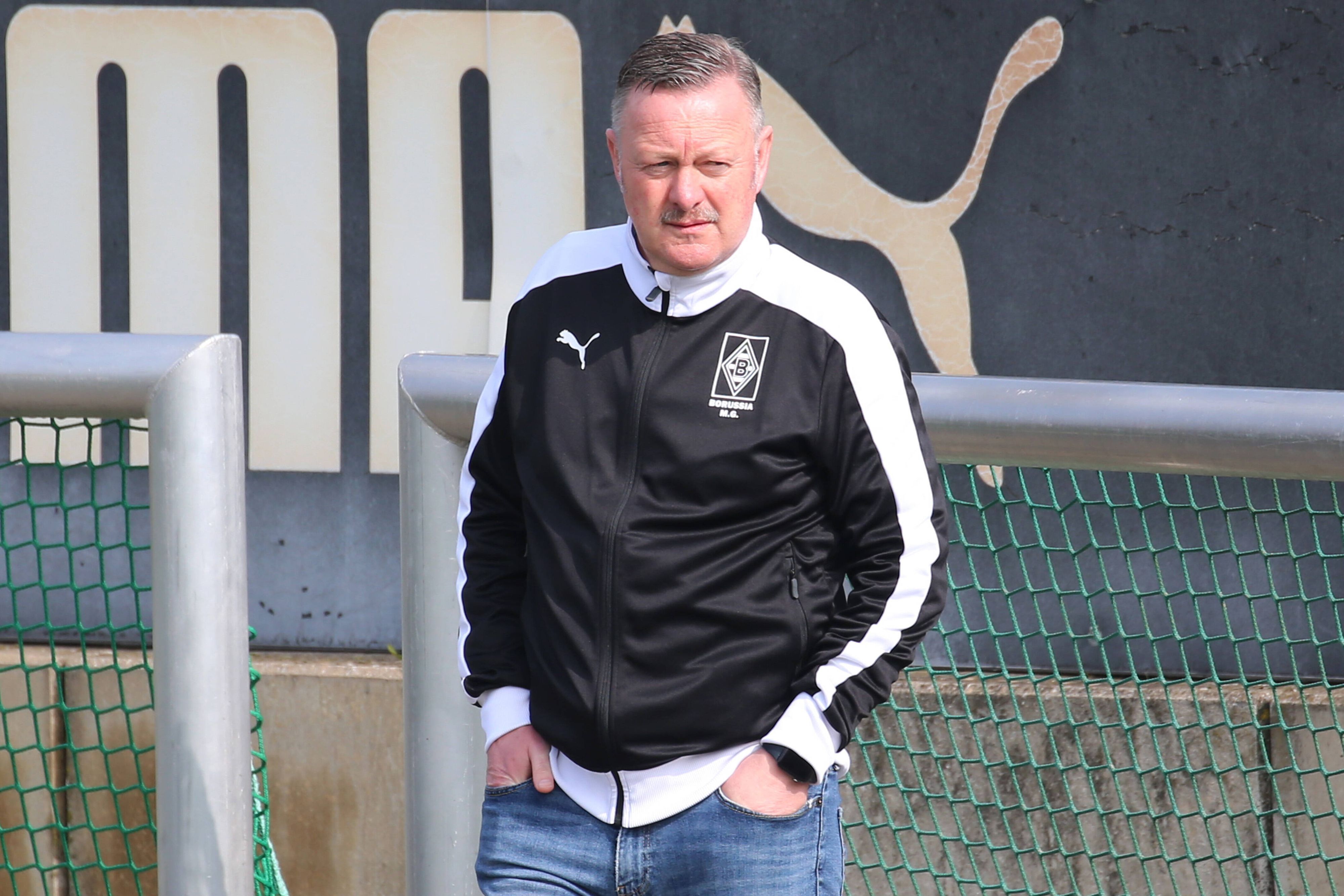 Gladbach-Manager Roland Virkus schaut sich am 14. April 2022 das Training der Profis im Borussia-Park an. Virkus hat die Hände in seinen vorderen Hosentaschen.