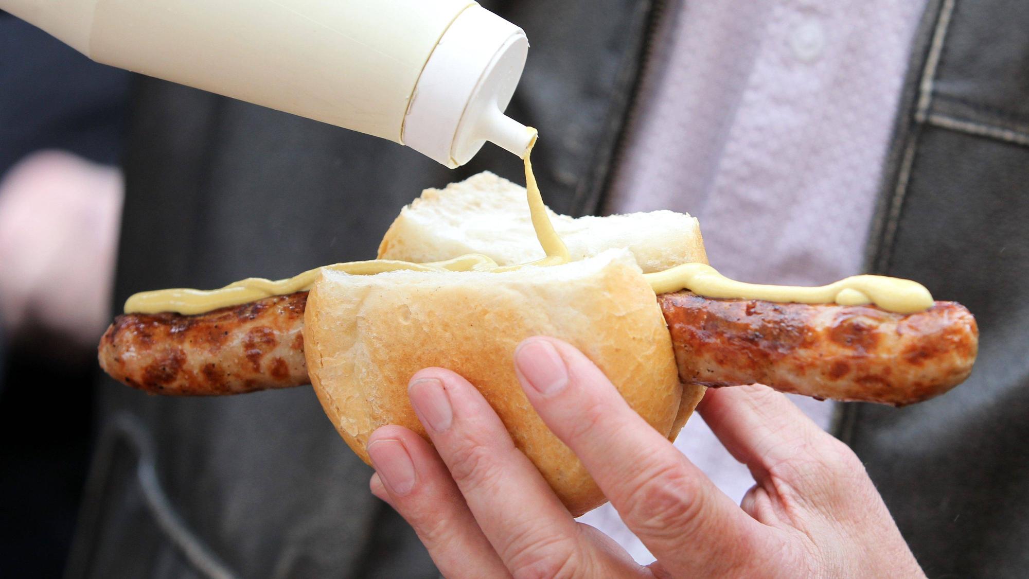Eine Bratwurst im Brötchen mit Senf. Dieses Symbolfoto stammt vom 26. März 2011. Die Aufnahme wurde auf dem Erfurter Domplatz erstellt.