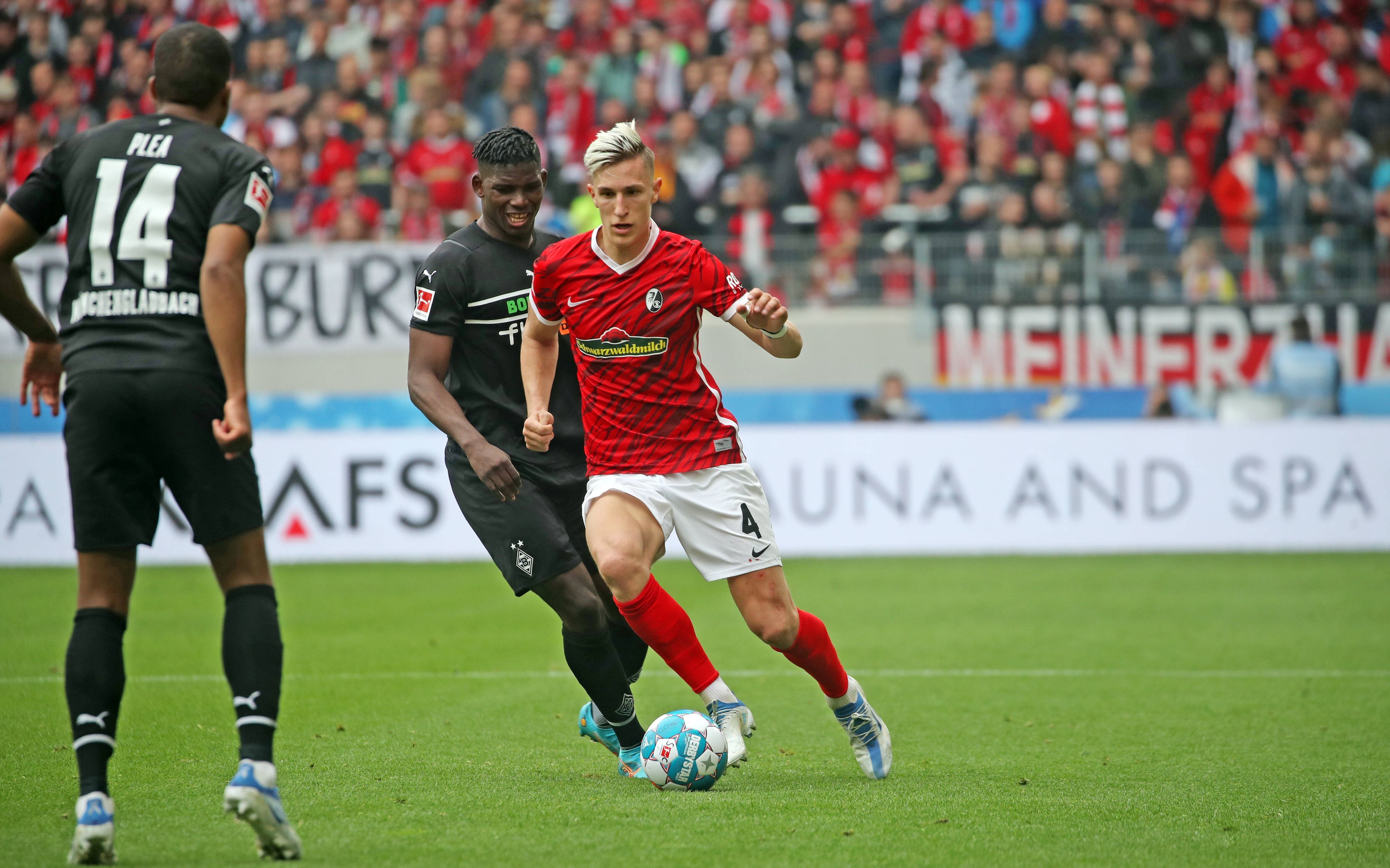 Gladbach-Stürmer Breel Embolo im Duell mit Nico Schlotterbeck (r.) vom SC Freiburg im Bundesliga-Duell am 23. April 2022. Plea (l.) schaut zu.