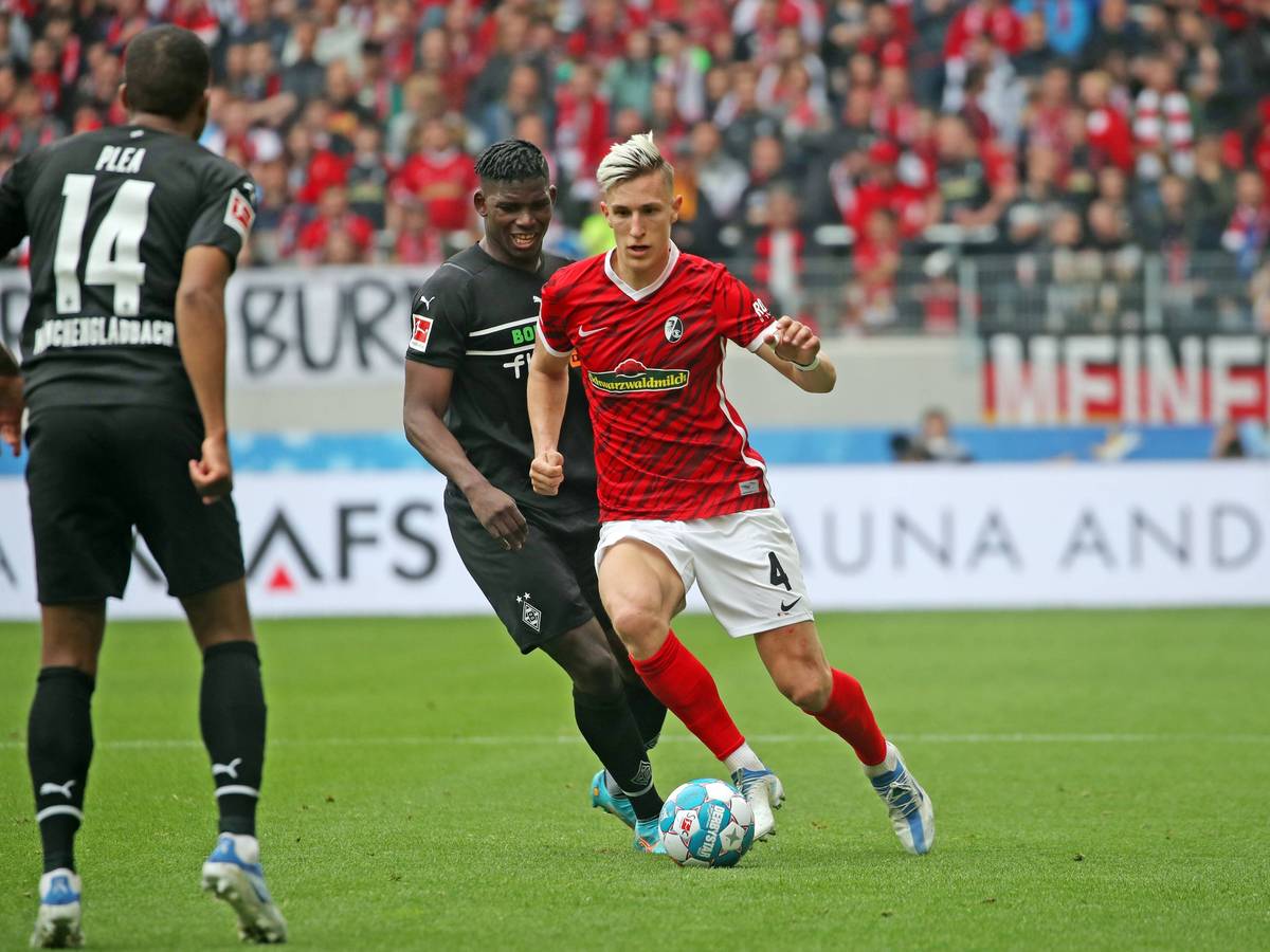 Gladbach-Stürmer Breel Embolo im Duell mit Nico Schlotterbeck (r.) vom SC Freiburg im Bundesliga-Duell am 23. April 2022. Plea (l.) schaut zu.