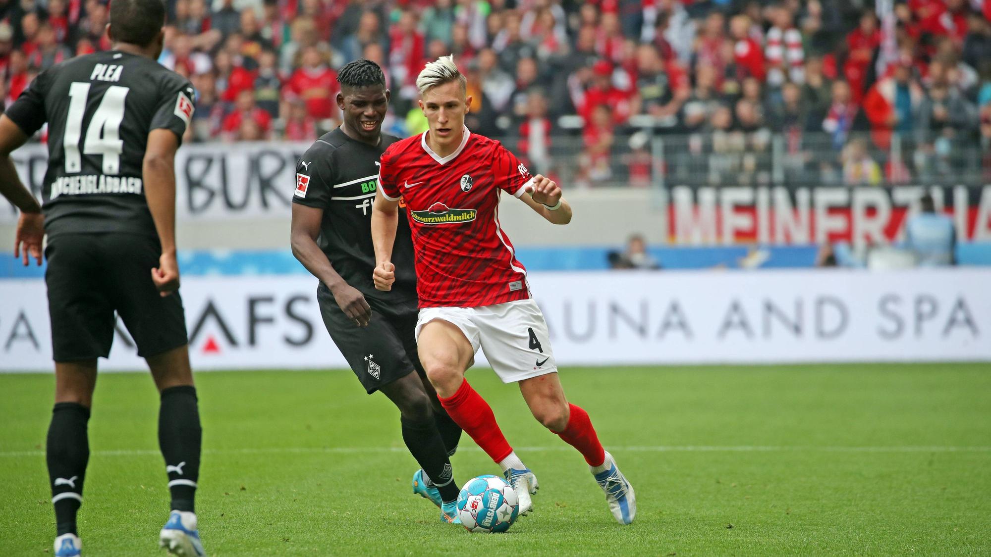 Gladbach-Stürmer Breel Embolo im Duell mit Nico Schlotterbeck (r.) vom SC Freiburg im Bundesliga-Duell am 23. April 2022. Plea (l.) schaut zu.