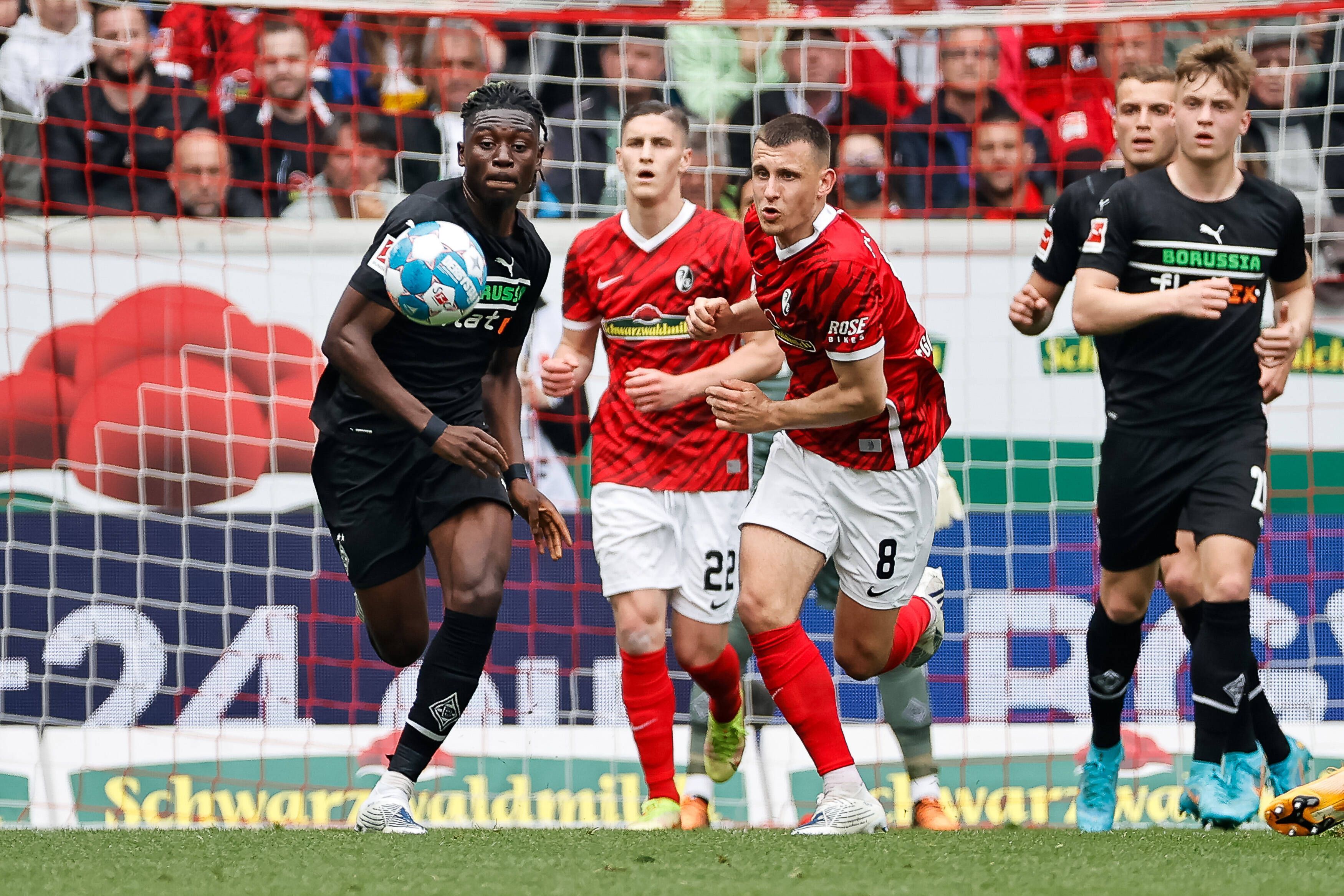 Kouadio Kone von Borussia Moenchengladbach im Kampf um den Ball mit Roland Sallai und Maximilian Eggestein vom SC Freiburg