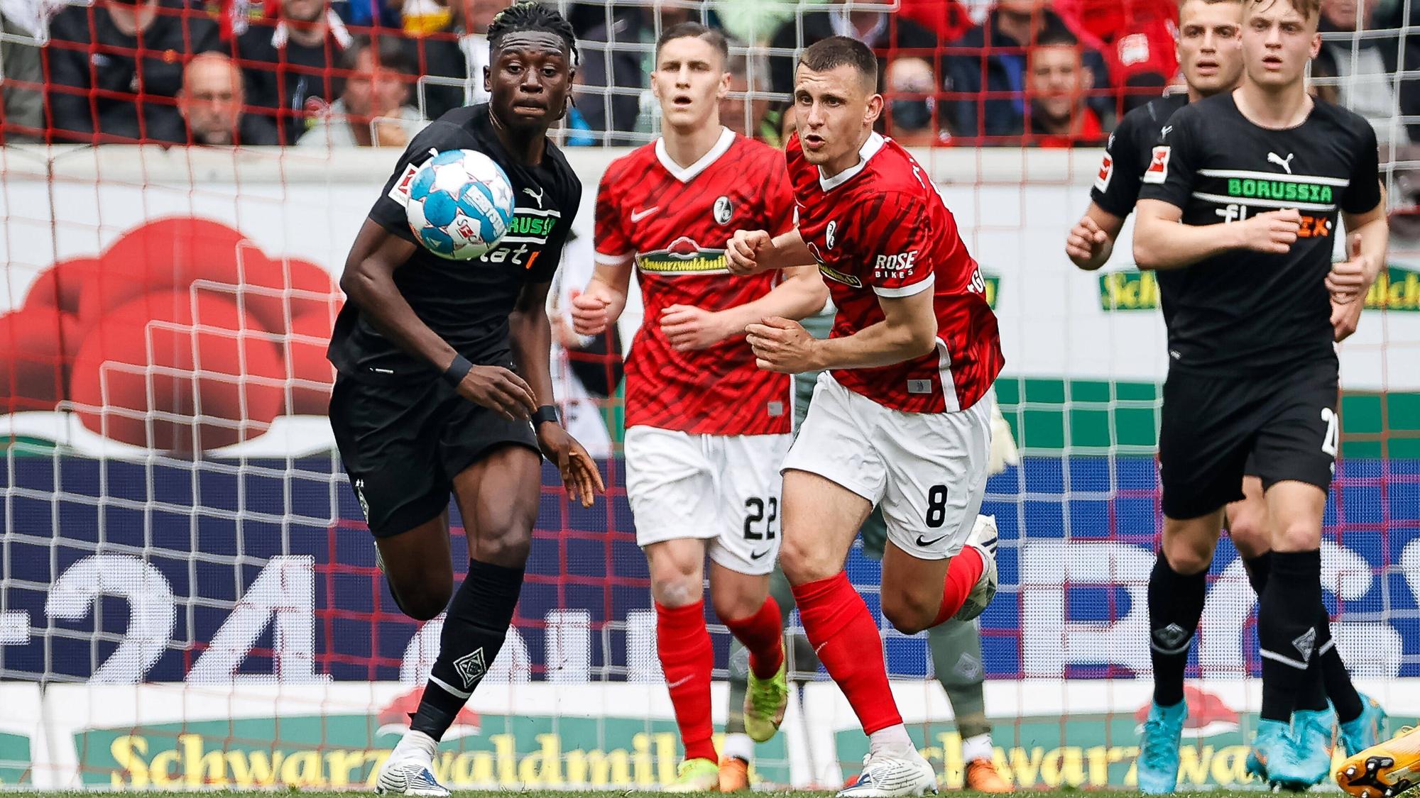Kouadio Kone von Borussia Moenchengladbach im Kampf um den Ball mit Roland Sallai und Maximilian Eggestein vom SC Freiburg