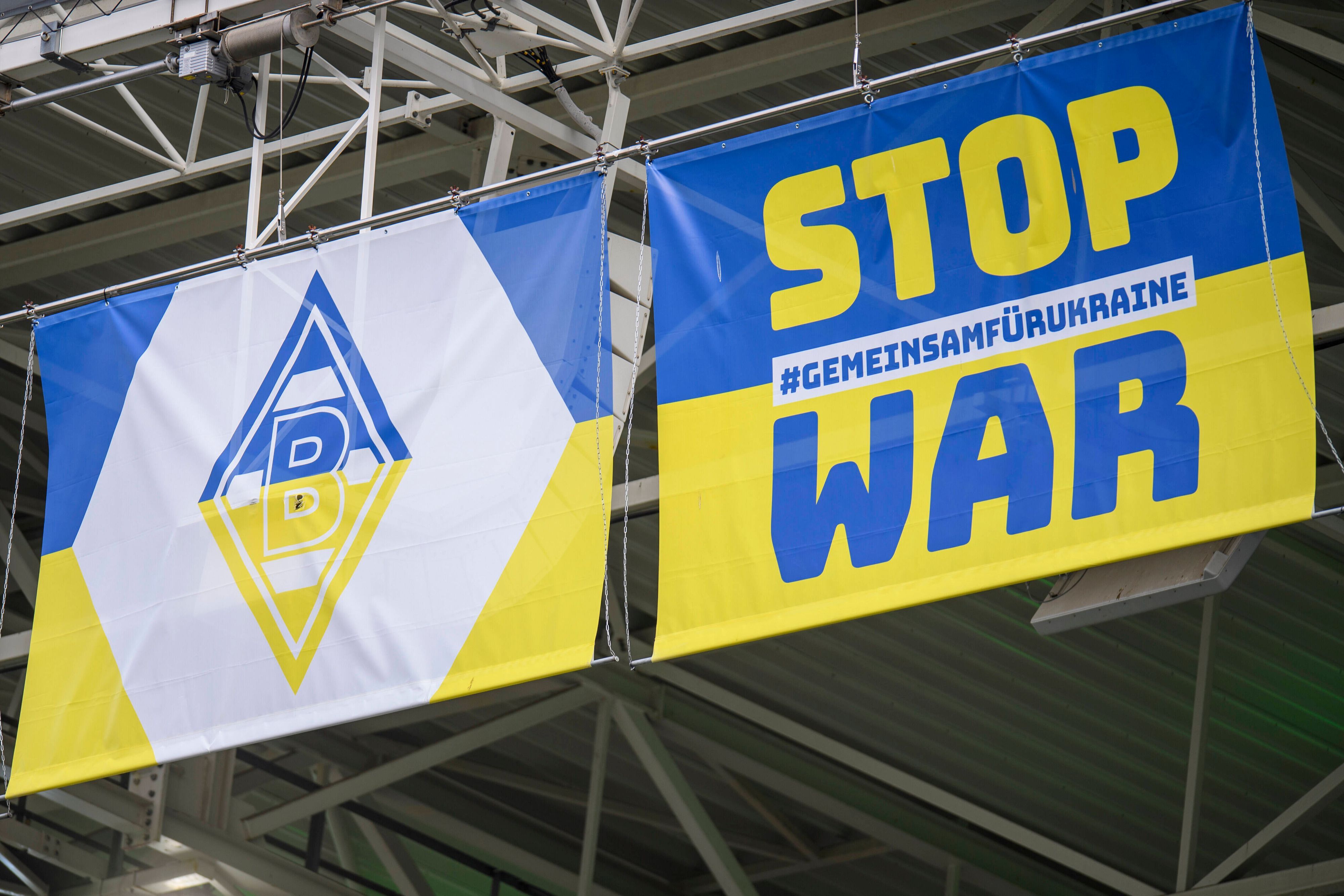 Zwei blau-gelbe Wappen mit Borussia-Logo und Anti-Kriegs-Slogan am 3. April 2022 im Borussia-Park.