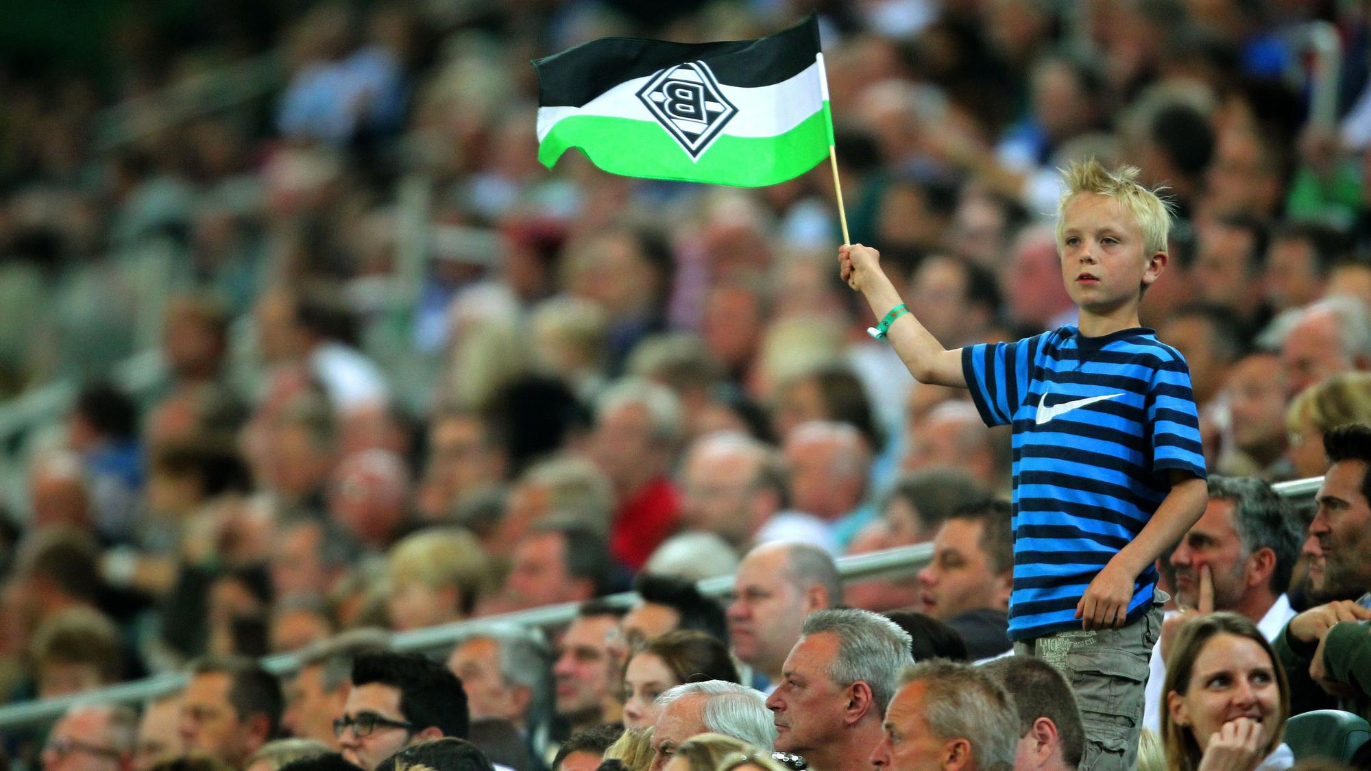 Zuschauerinnen und Zuschauer im Borussia-Park. Dieses Fan-Foto stammt von der Partie zwischen Borussia Mönchengladbach und dem VfL Wolfsburg am 19. August 2011. Ein junger Fan schwenkt seine Gladbach-Fahne.