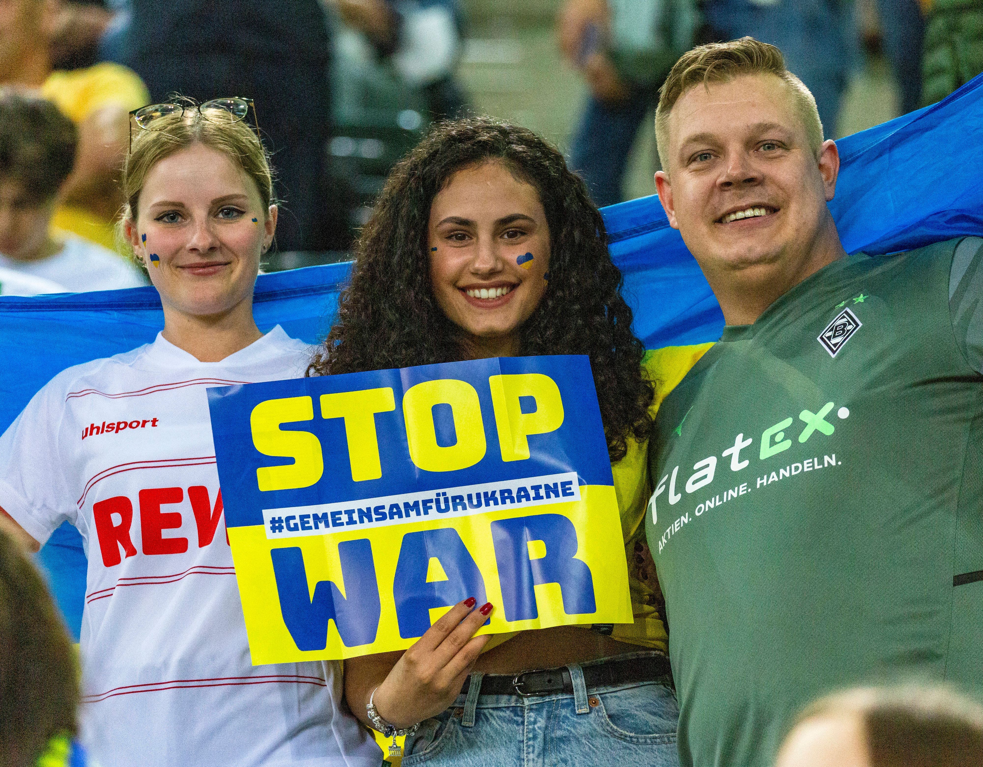 „Stop War“-Aufforderung von ukrainischen und deutschen Zuschauerinnen und Zuschauer während des Benefizspiels von Borussia Mönchengladbach gegen die Nationalmannschaft der Ukraine am 11. Mai 2022 im Borussia-Park. Auch eine Anhängerin des 1. FC Köln ist dabei.