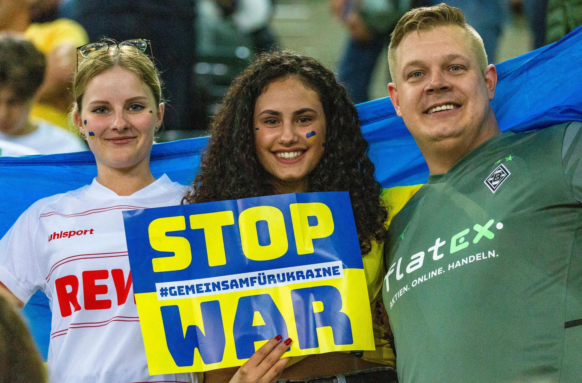 „Stop War“-Aufforderung von ukrainischen und deutschen Zuschauerinnen und Zuschauer während des Benefizspiels von Borussia Mönchengladbach gegen die Nationalmannschaft der Ukraine am 11. Mai 2022 im Borussia-Park. Auch eine Anhängerin des 1. FC Köln ist dabei.