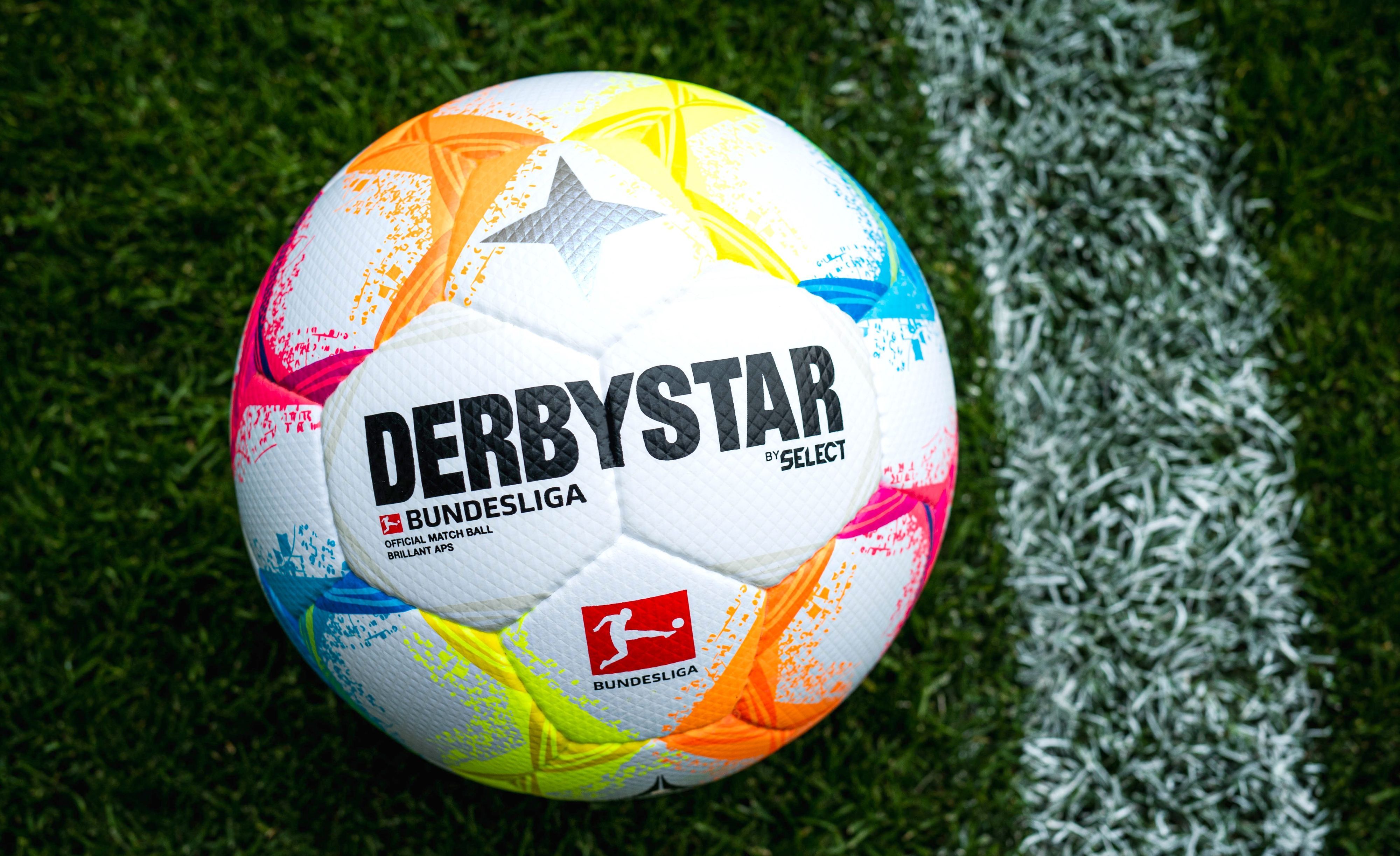 Der neue Bundesliga-Spielball mit vielen farblichen Details liegt auf Fußball-Rasen.