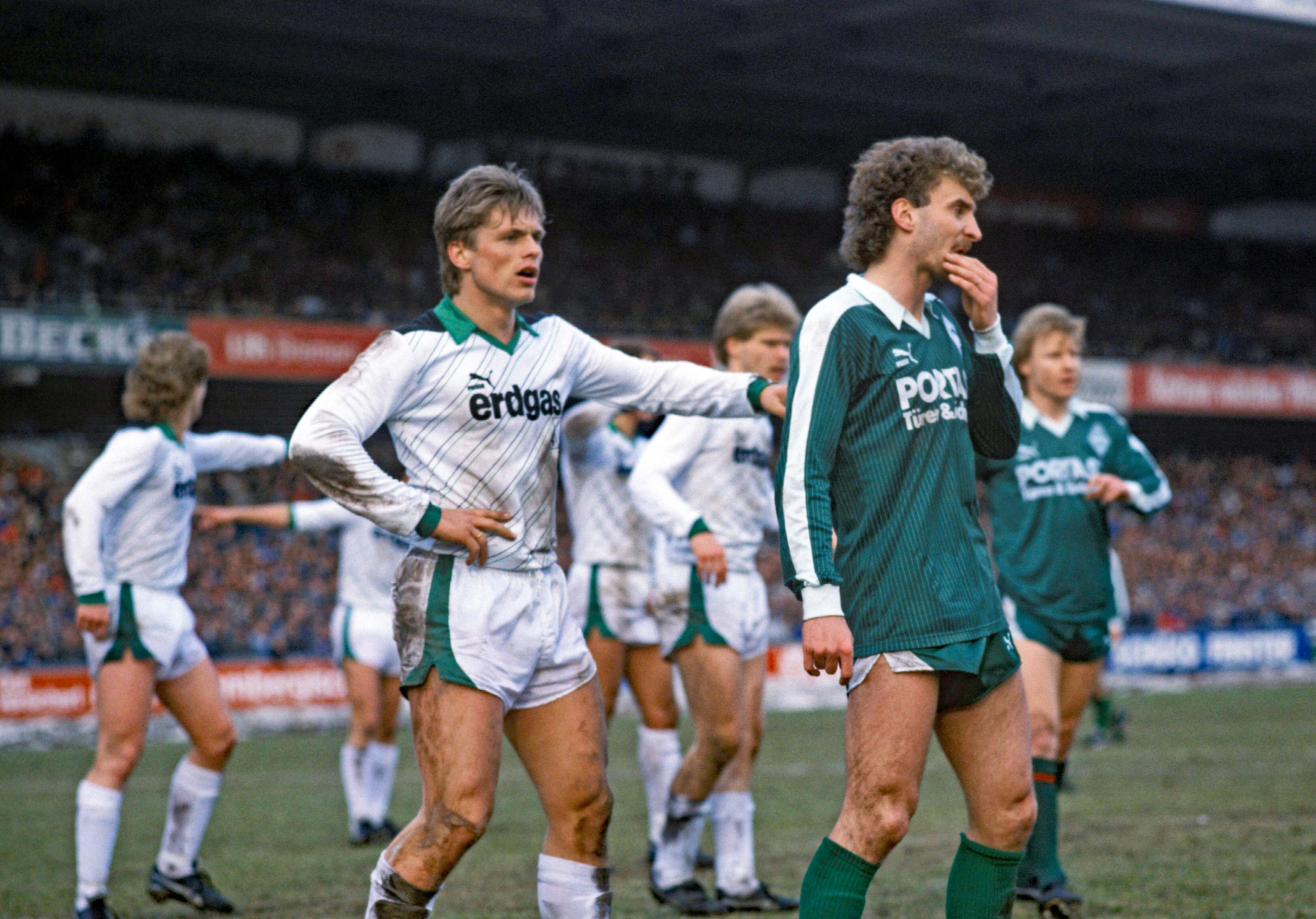 Uli Borowka (l.), ehemaliger Spieler von Borussia Mönchengladbach, hier zu sehen am 21. März 1987 mit Duell mit Werder-Bremen-Stürmer Rudi Völler (r.) im Weserstadion. Völler und Borowka schauen nach vorne in Erwartung einer Hereingabe.
