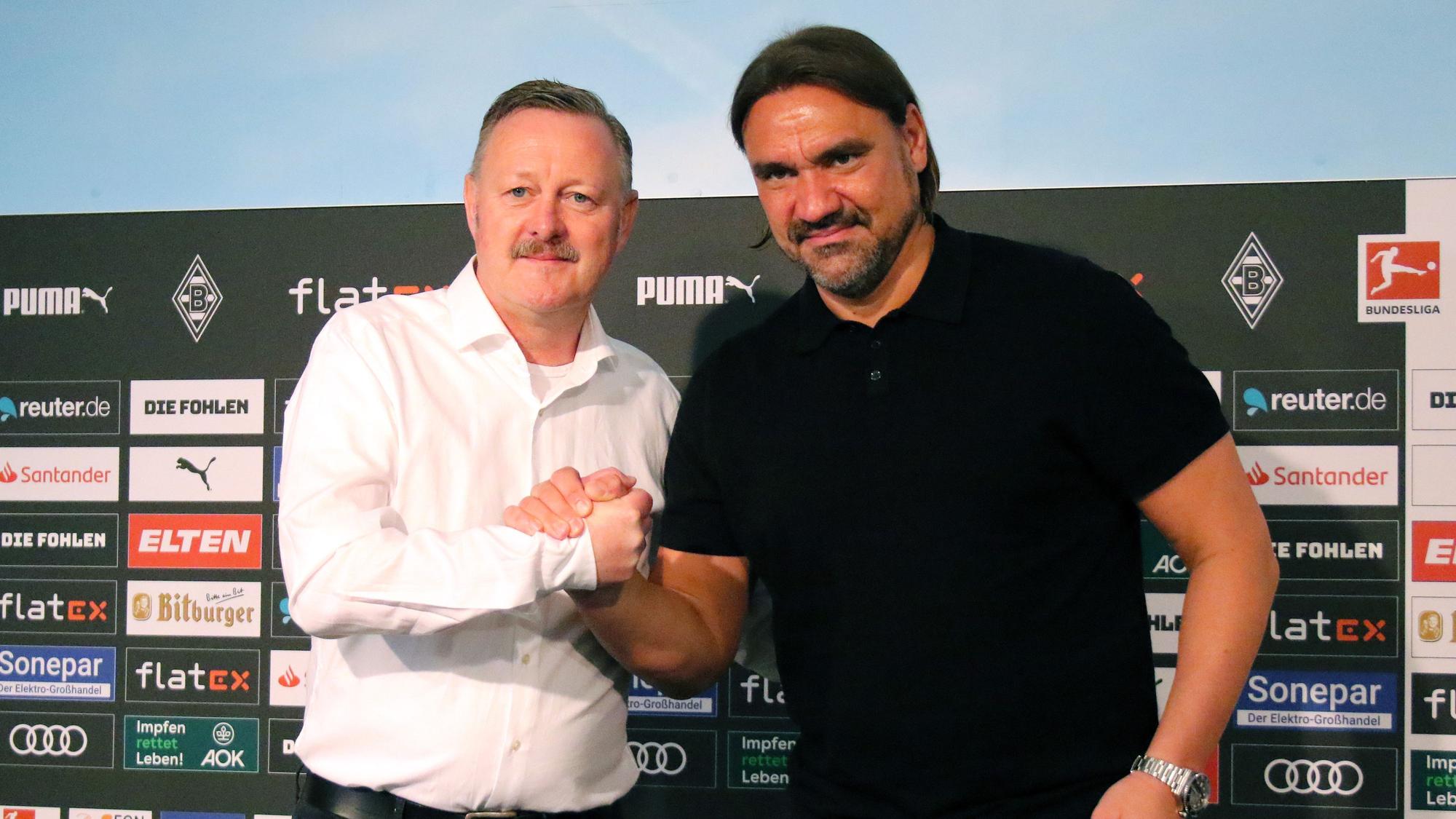 Sportdirektor Roland Virkus (l.) und Trainer Daniel Farke von Borussia Mönchengladbach bei einer Pressekonferenz am 5. Juni 2022. Farke und Virkus stehen vor einer Pressewand und geben sich die Hand.