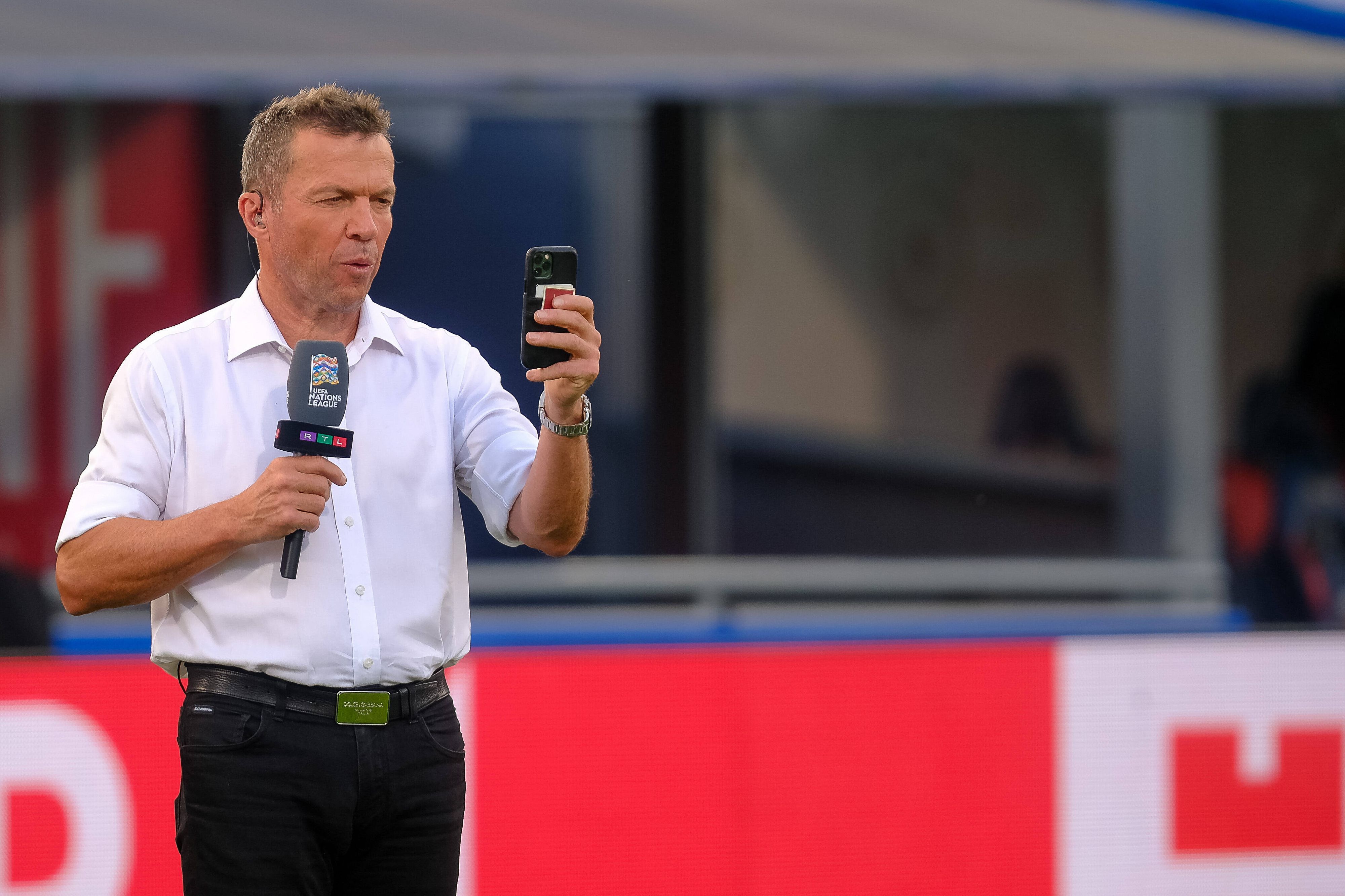 Ein Selfie muss sein! Weltmeister und TV-Experte Lothar Matthäus am 4. Juni 2022 in Bologna. Matthäus hält ein Smartphone in der linken Hand, in der rechten ein Mikrofon.