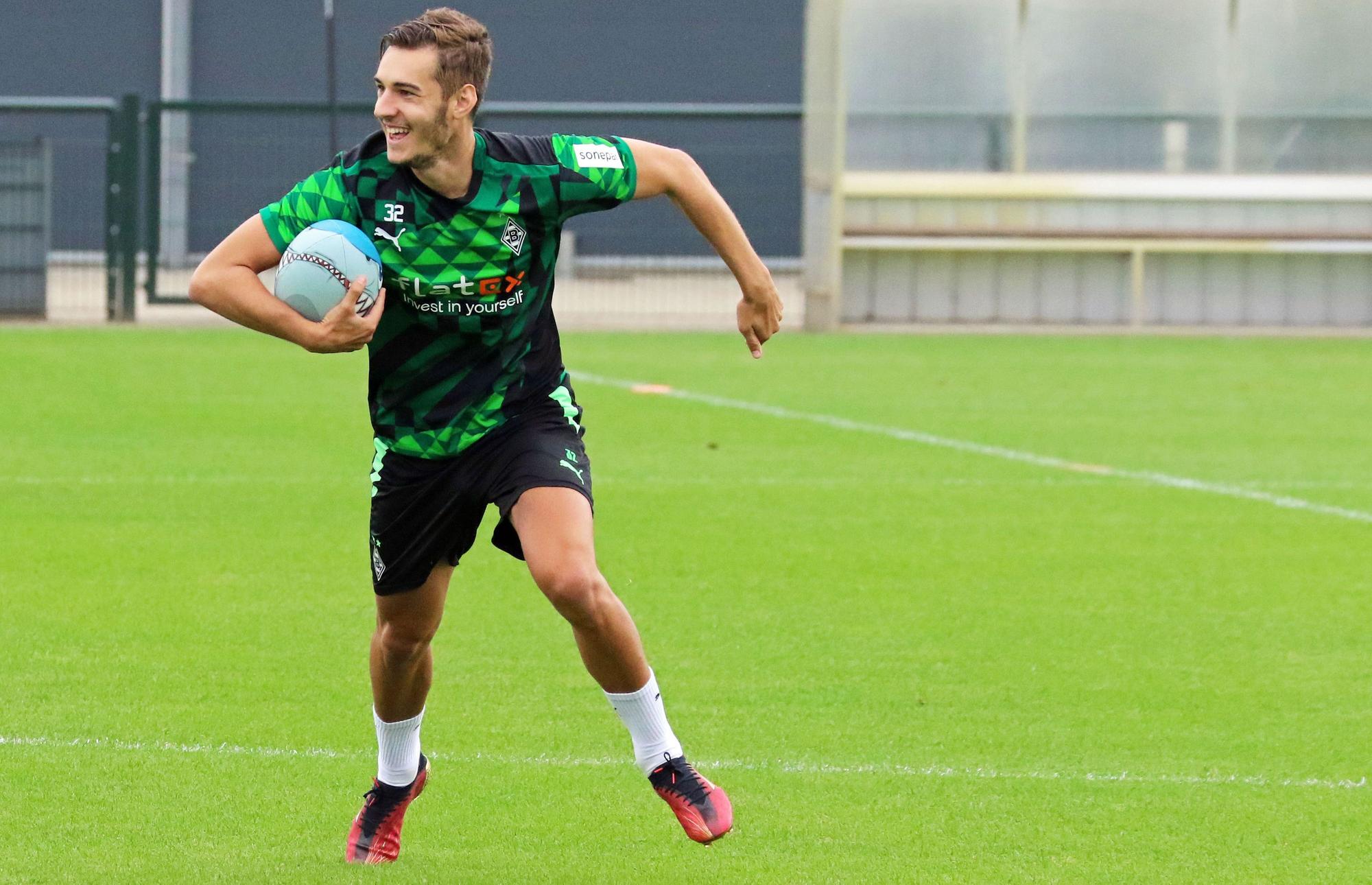Gladbach-Profi Florian Neuhaus hat sichtlich Spaß beim Rugby. Dieses Foto stammt vom Training am 27. Juni 2022 im Borussia-Park. Neuhaus hält den Rugby-Ball fest und läuft.