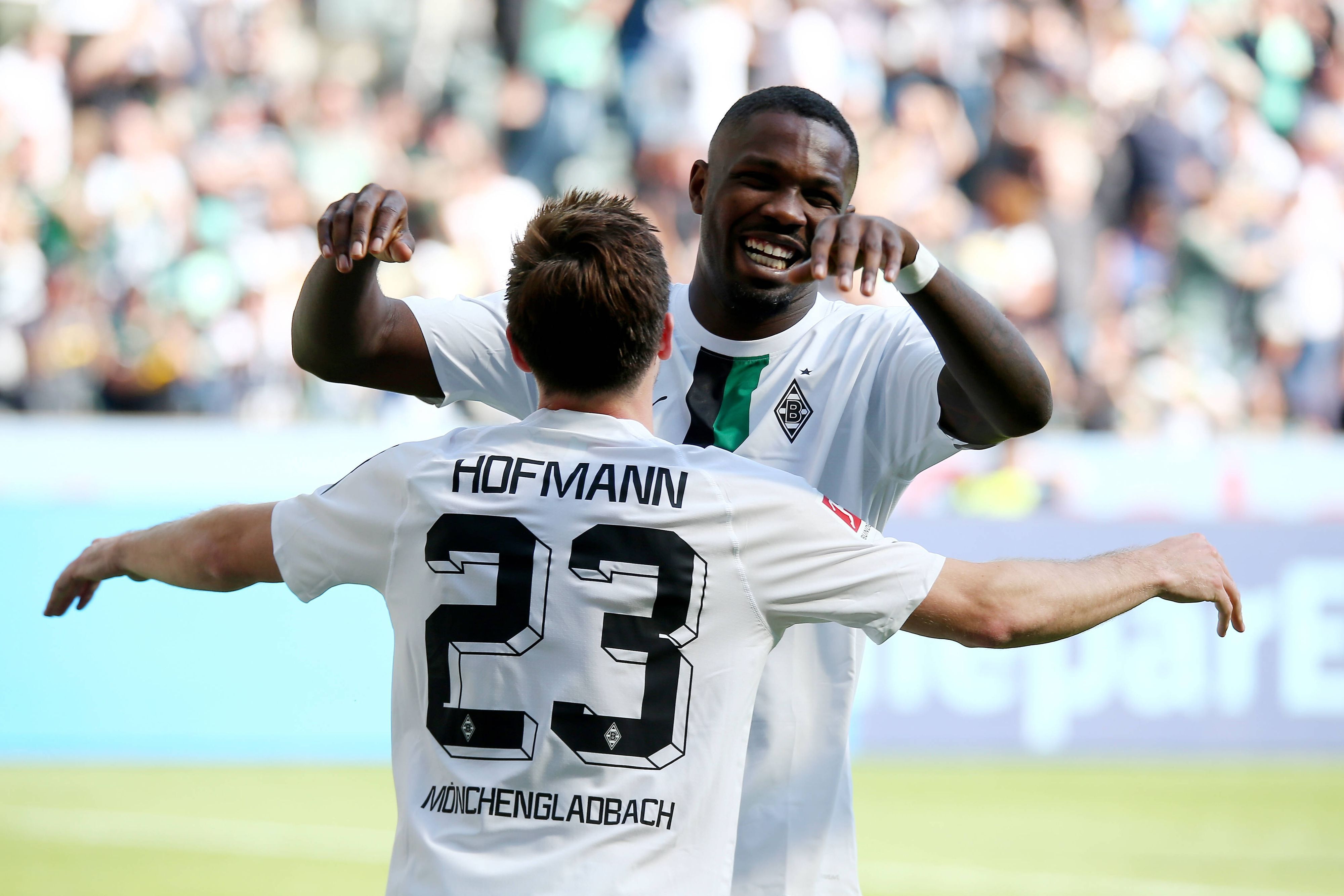 Die Gladbach-Profis Marcus Thuram und Jonas Hofmann jubeln in neuen Trikots beim Bundesliga-Heimsieg (5:1) gegen die TSG Hoffenheim (14. Mai 2022). Am ersten Spieltag der neuen Saison geht es für die Borussia erneut gegen Hoffenheim. Hofmann und Thuram (im Hintergrund) umarmen sich.
