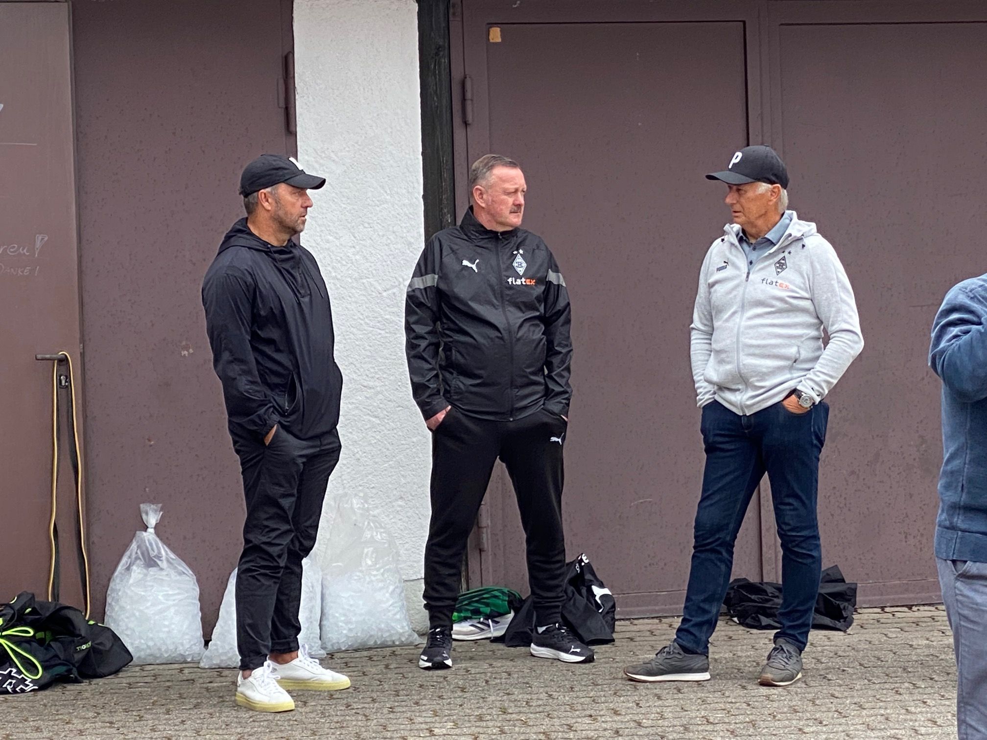 Bundestrainer Hansi Flick, Gladbach-Manager Roland Virkus und Vizepräsident Rainer Bonhof (v.l.n.r.) unterhalten sich am Rande des Borussia-Trainings am Donnerstag (7. Juli 2022) in Rottach-Egern.