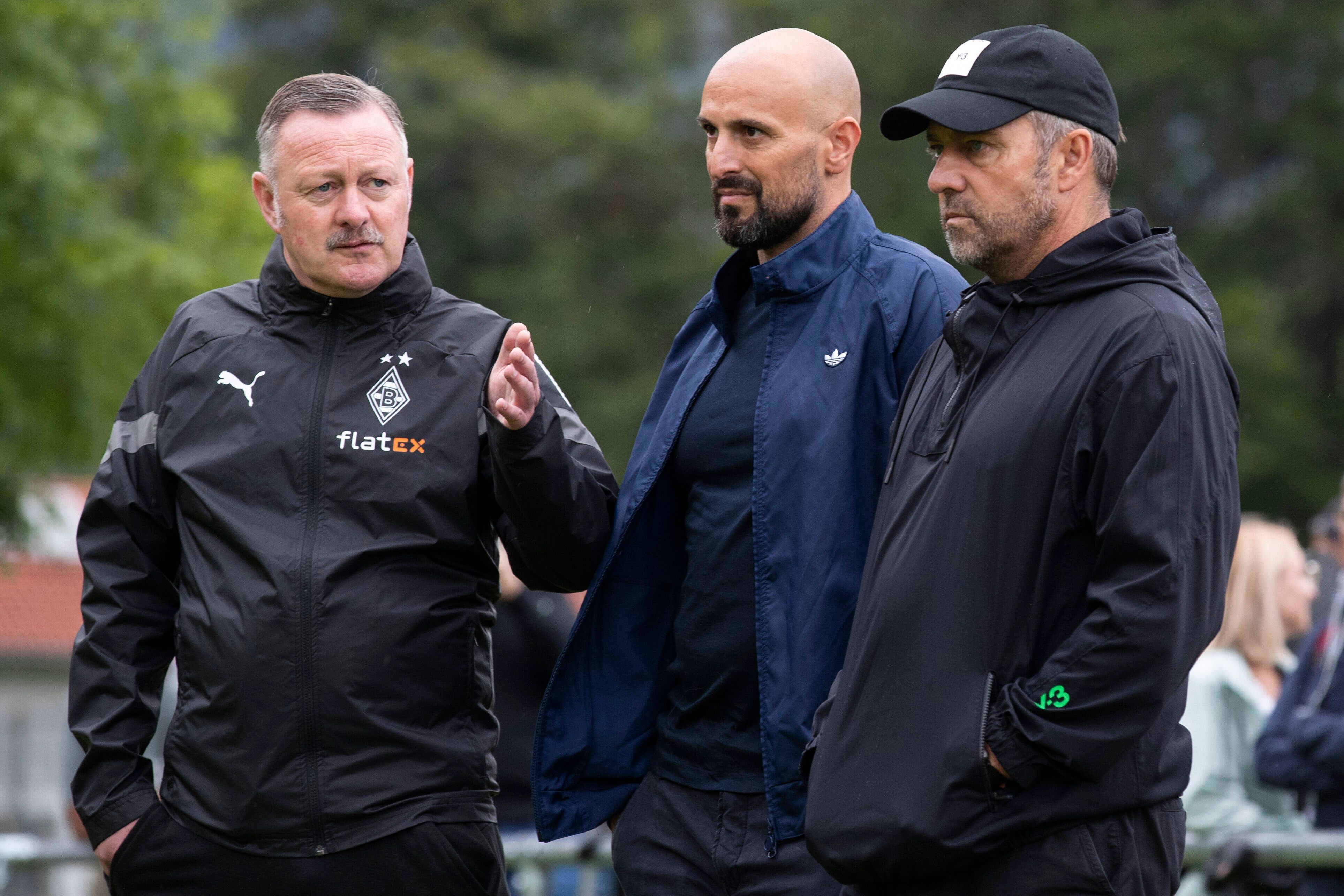 Gladbach-Manager Roland Virkus (l.) im Gespräch DFB-Bundestrainer Hansi Flick (r.) und U21-Nationalcoach Antonio Di Salvo (r.) im Trainingslager der Borussia am Tegernsee in Rottach-Egern. Dieses Foto stammt vom 7. Juli 2022. Virkus macht eine Geste mit der linken Hand.
