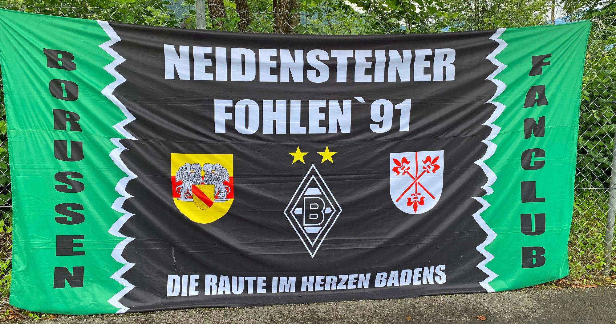 Das Banner des Gladbach-Fanklubs „Neidensteiner Fohlen '91“ ist auf der Sportanlage Birkenmoos in Rottach-Egern zu sehen. Die Fahne hängt an einem Zaun.