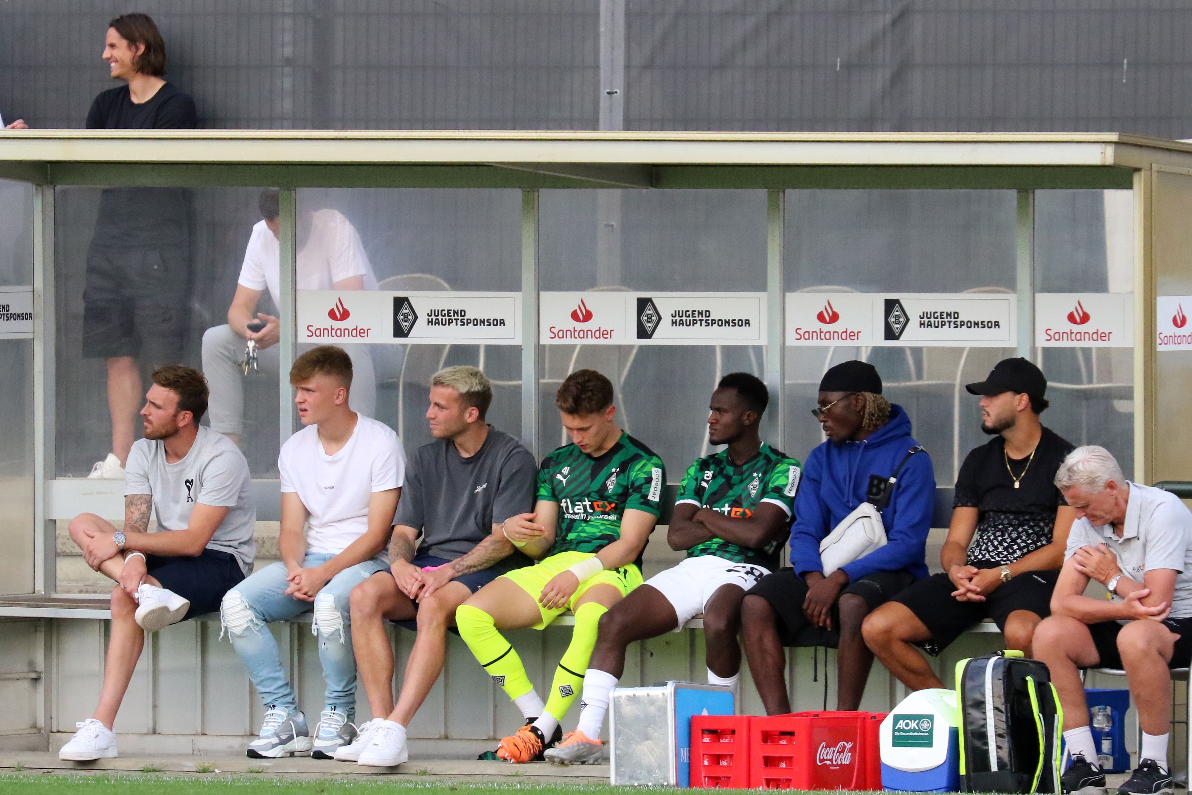 Prominent besetzte Zuschauerbank, mit unter anderem Ramy Bensebaini (2. v. r.) und Luca Netz (2. v. l.) im Rahmen des Testspiels zwischen Borussia Mönchengladbach und Viktoria Köln am 13. Juli 2022.
