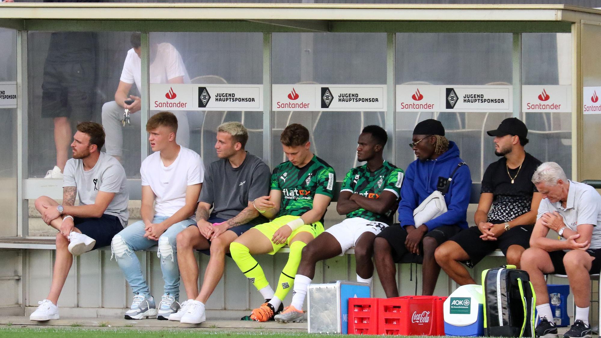 Prominent besetzte Zuschauerbank, mit unter anderem Ramy Bensebaini (2. v. r.) und Luca Netz (2. v. l.) im Rahmen des Testspiels zwischen Borussia Mönchengladbach und Viktoria Köln am 13. Juli 2022.