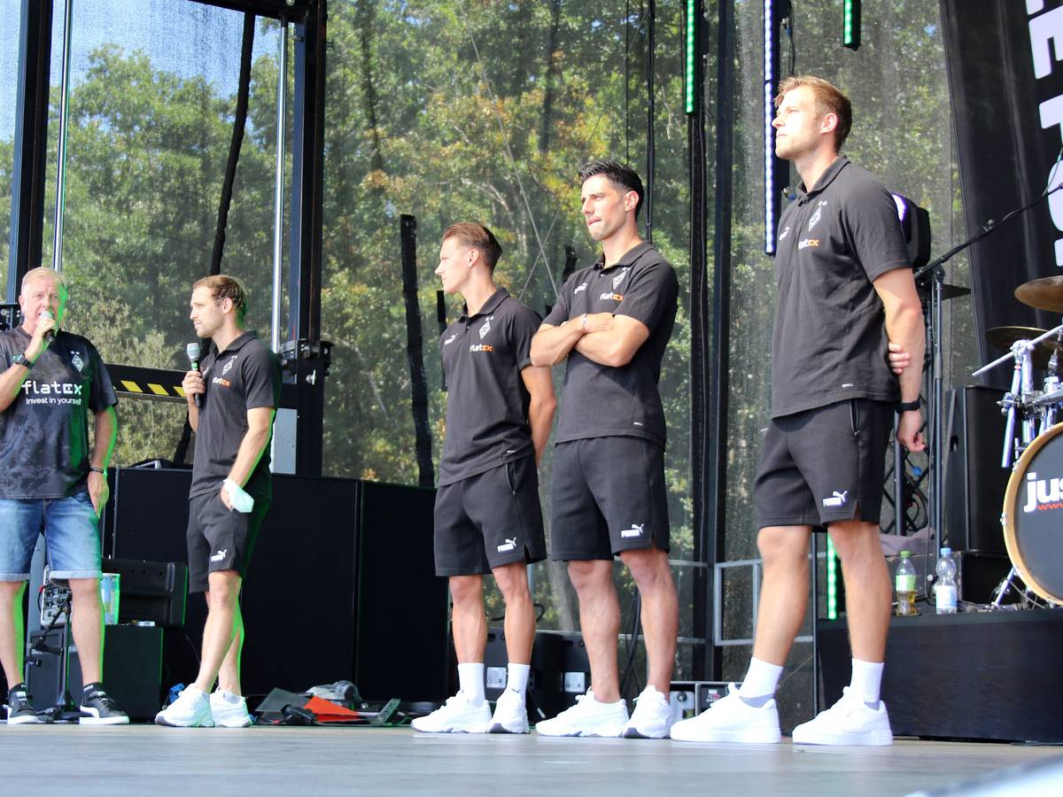Moderator Frank Schiffers mit den Profis Tony Jantschke, Hannes Wolf, Lars Stindl und Torwarttrainer Fabian Otte (v.l.n.r) am 24. Juli 2022 bei der Saisoneröffnung von Borussia Mönchengladbach. Die Gruppe steht auf einer Bühne, Schiffers und Jantschke sprechen in ein Mikrofon.