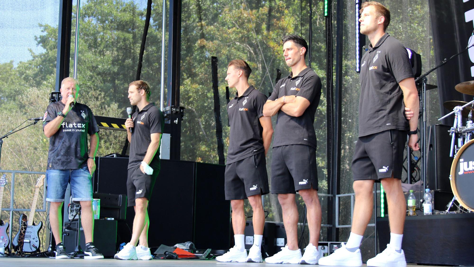 Moderator Frank Schiffers mit den Profis Tony Jantschke, Hannes Wolf, Lars Stindl und Torwarttrainer Fabian Otte (v.l.n.r) am 24. Juli 2022 bei der Saisoneröffnung von Borussia Mönchengladbach. Die Gruppe steht auf einer Bühne, Schiffers und Jantschke sprechen in ein Mikrofon.