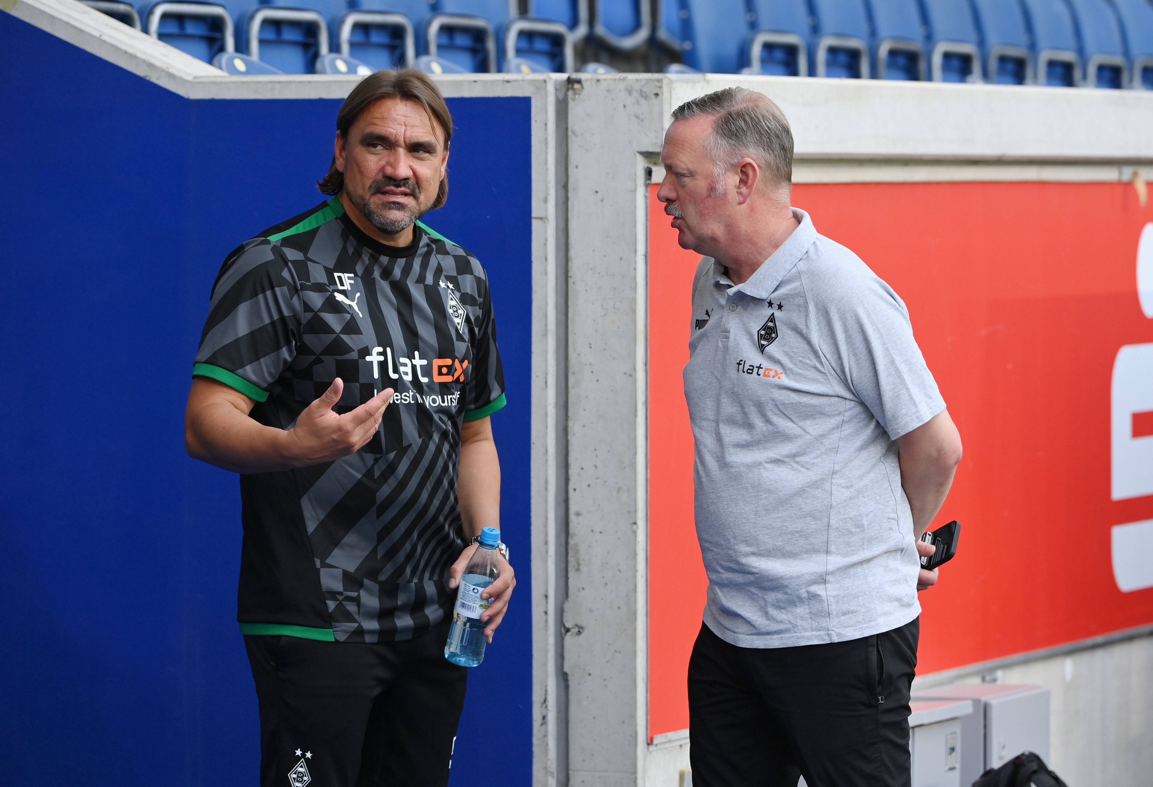 Trainer Daniel Farke von Borussia Mönchengladbach am 17. Juli 2022 in Duisburg im Gespräch mit Sportdirektor Roland Virkus. Farke gestikuliert mit der rechten Hand, Virkus hat die Arme hinter dem Rücken verschränkt.