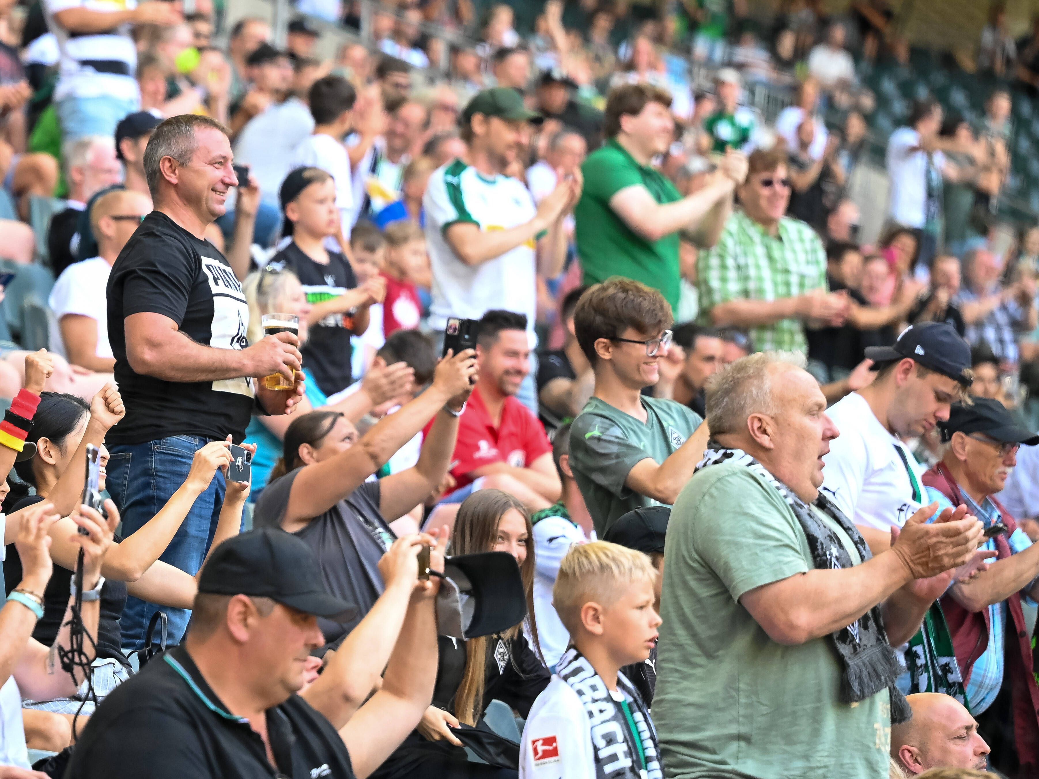 Fans der Gladbacher Borussia bejubeln am 23. Juli 2022 im Borussia-Park einen Treffer der Fohlen-Elf im Testduell gegen Real Sociedad San Sebastian. Ein Anhänger hält einen Bierbecher in seinen Händen. Die Fans klatschen und machen Handy-Fotos.