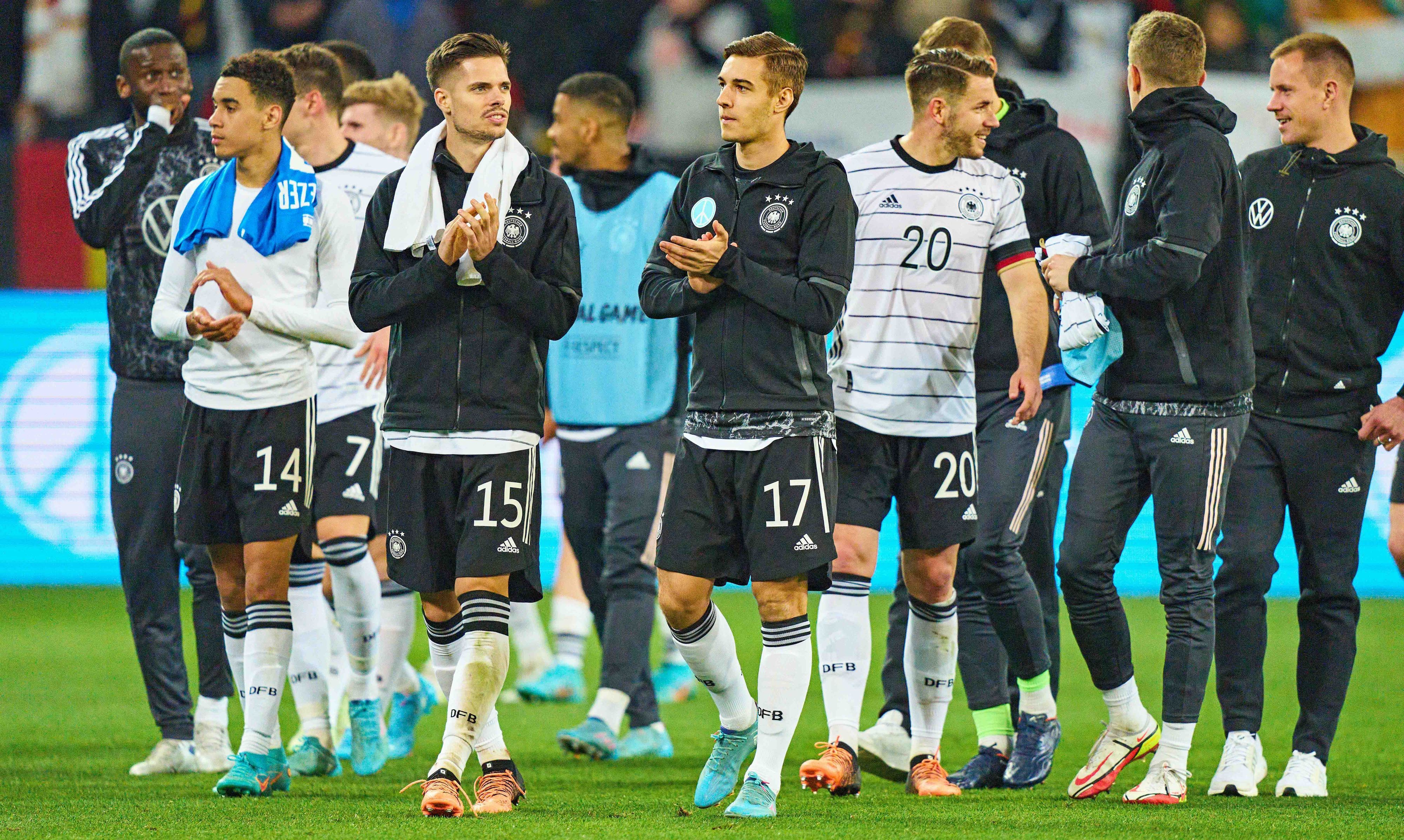 Gladbach-Profi Florian Neuhaus (rechts, im Vordergrund) schreitet gemeinsam mit Julian Weigl (l.) nach dem Länderspiel der DFB-Elf gegen Israel am 26. März 2022 über den Rasen der Arena in Sinsheim. Neuhaus und Weigl klatschen in die Hände.