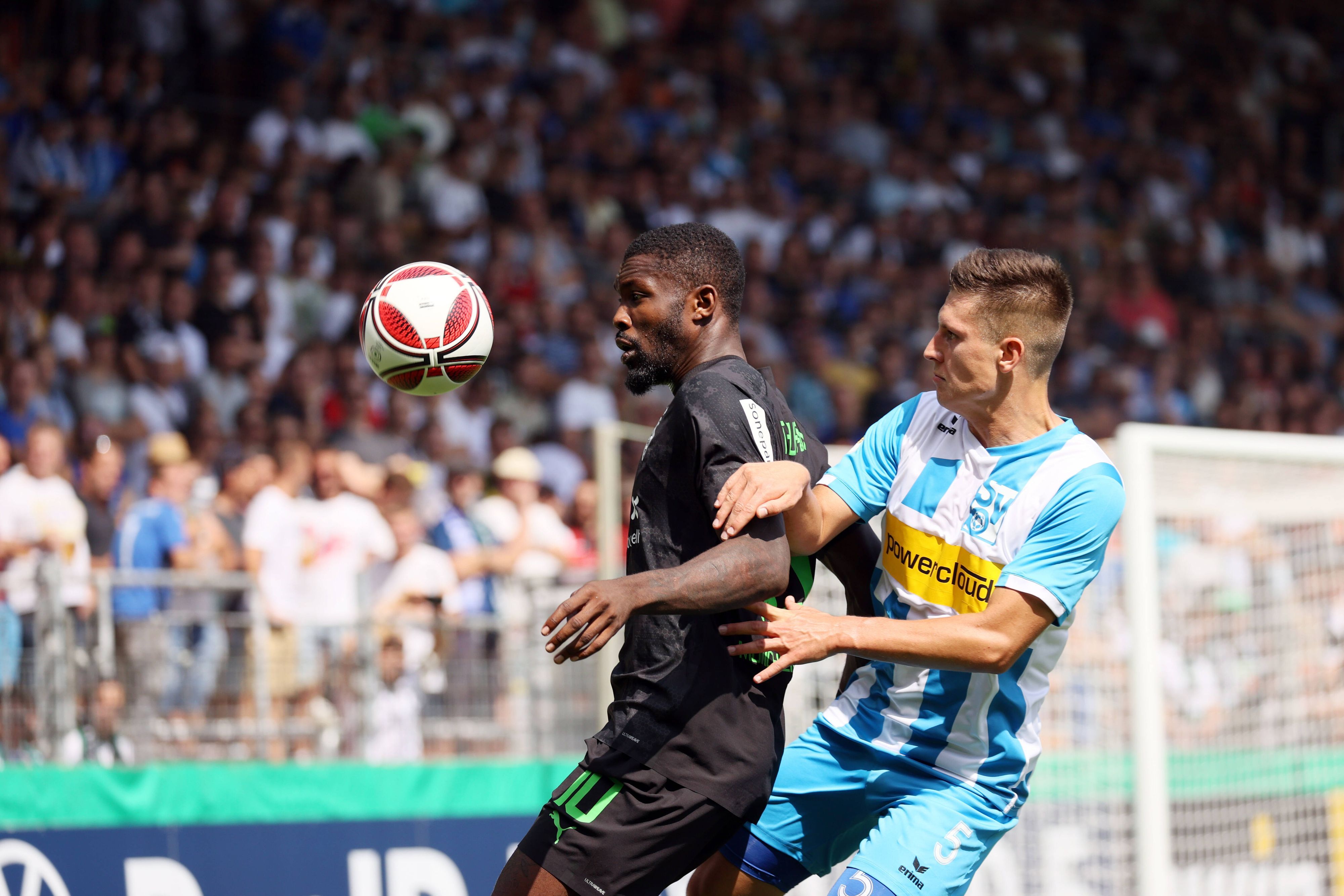 Marcus Thuram von Borussia Mönchengladbach (li.) beim DFB-Pokalspiel beim SV Oberachern am 31. Juli 2022 im Zweikampf mit Noah Zwick (re.). Thuram schirmt den springenden Ball mit seinem Körper ab.