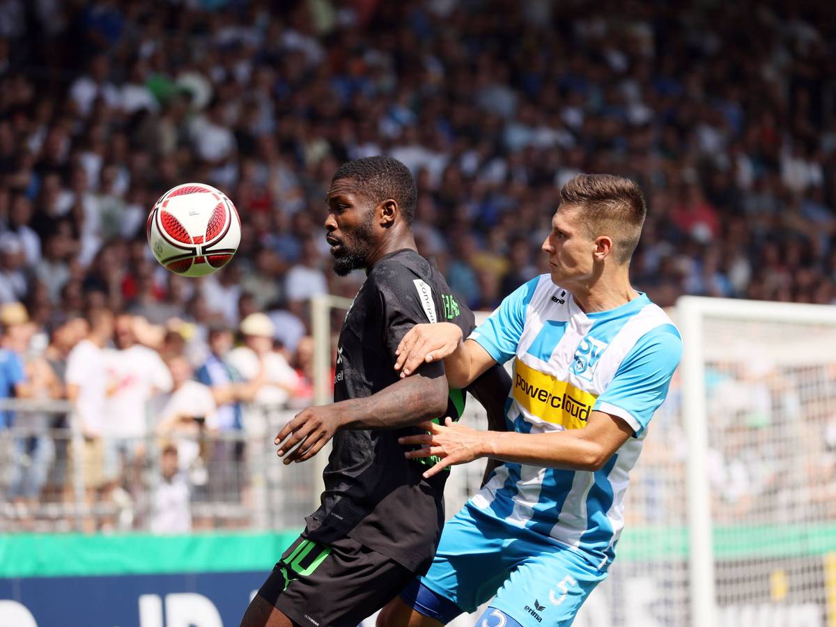 Marcus Thuram von Borussia Mönchengladbach (li.) beim DFB-Pokalspiel beim SV Oberachern am 31. Juli 2022 im Zweikampf mit Noah Zwick (re.). Thuram schirmt den springenden Ball mit seinem Körper ab.
