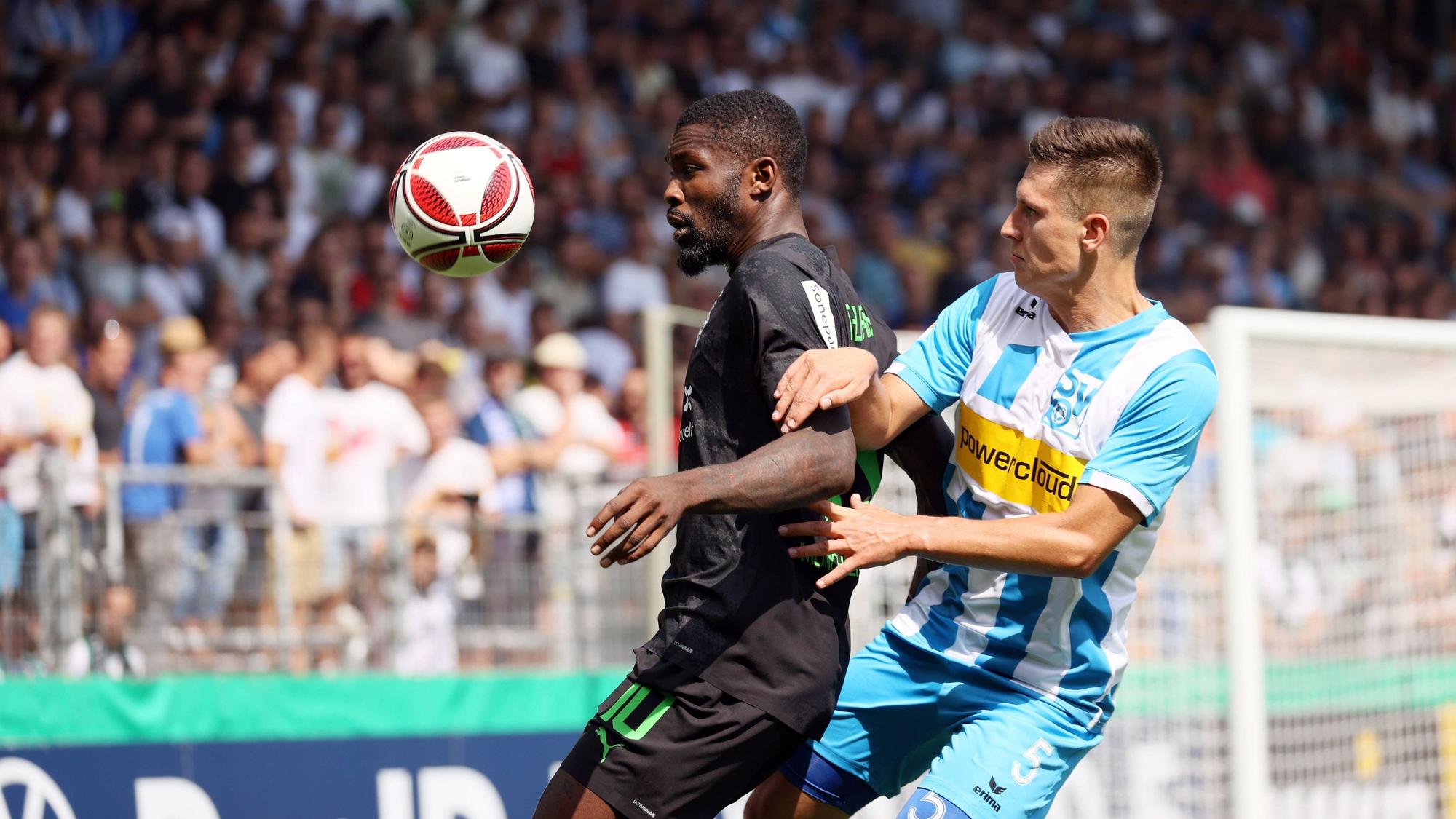 Marcus Thuram von Borussia Mönchengladbach (li.) beim DFB-Pokalspiel beim SV Oberachern am 31. Juli 2022 im Zweikampf mit Noah Zwick (re.). Thuram schirmt den springenden Ball mit seinem Körper ab.