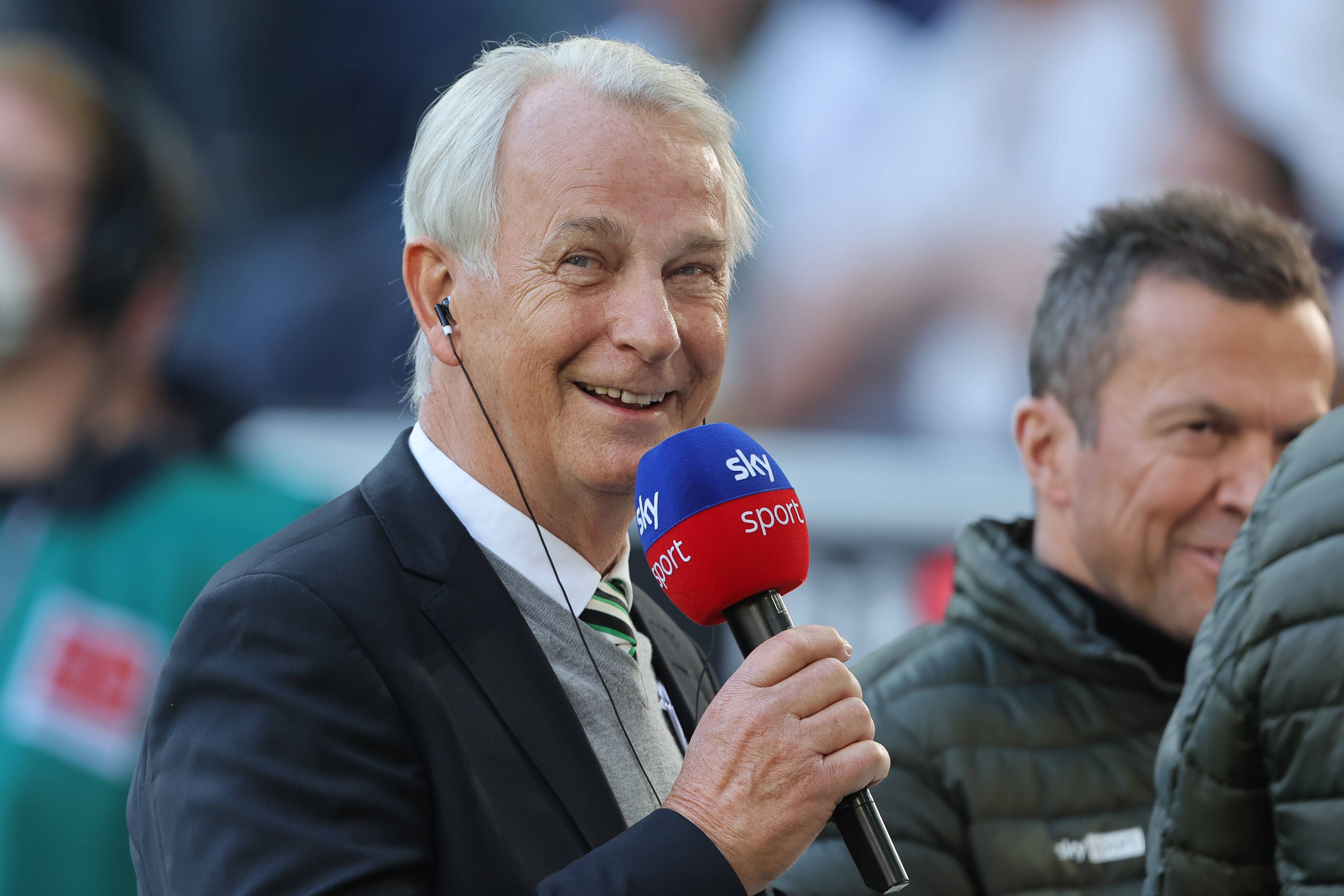 Rainer Bonhof, Vize-Präsident von Borussia Mönchengladbach im Interview mit dem TV-Sender Sky. Dieses Foto entstand vor dem Spiel gegen den 1. FC Köln am 16. April 2022. Bonhof hält ein Mikrofon in der rechten Hand und lächelt.