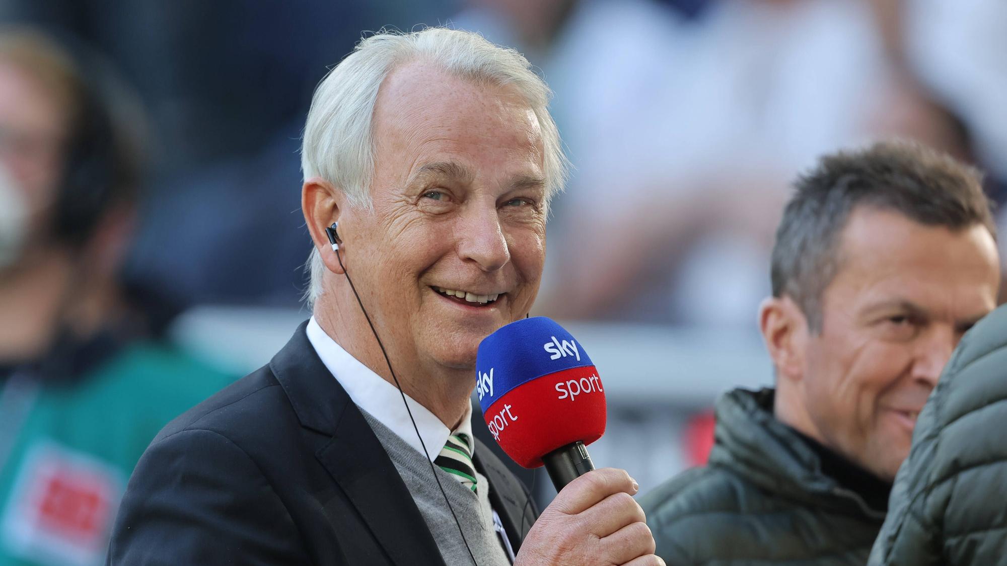 Rainer Bonhof, Vize-Präsident von Borussia Mönchengladbach im Interview mit dem TV-Sender Sky. Dieses Foto entstand vor dem Spiel gegen den 1. FC Köln am 16. April 2022. Bonhof hält ein Mikrofon in der rechten Hand und lächelt.