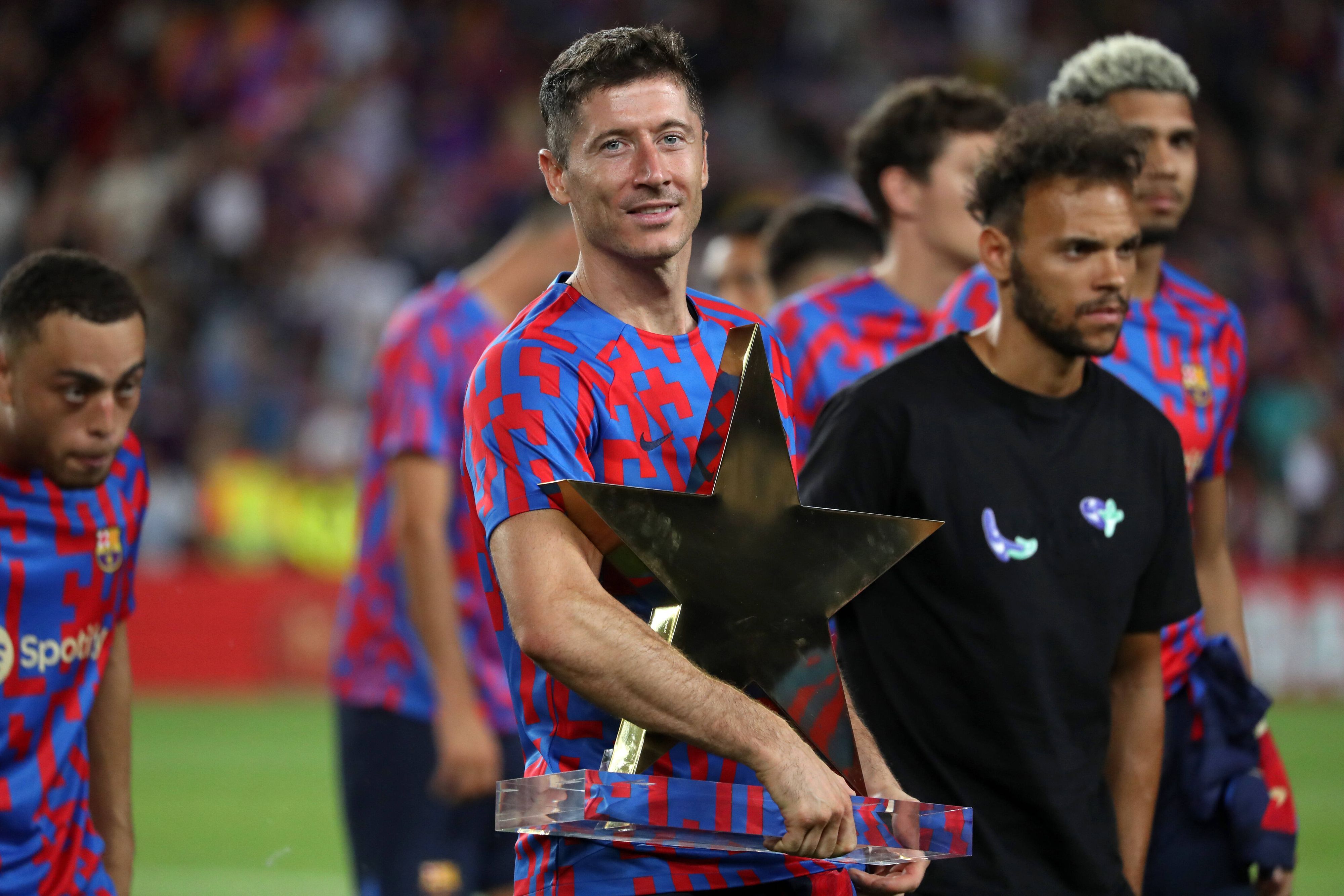 Stürmer Robert Lewandowski, neuer Team-Kollege von Marc-André ter Stegen beim FC Barcelona, hält am 7. August 2022 die Joan-Gamper-Trophäe im Arm. Lewandowski lächelt.