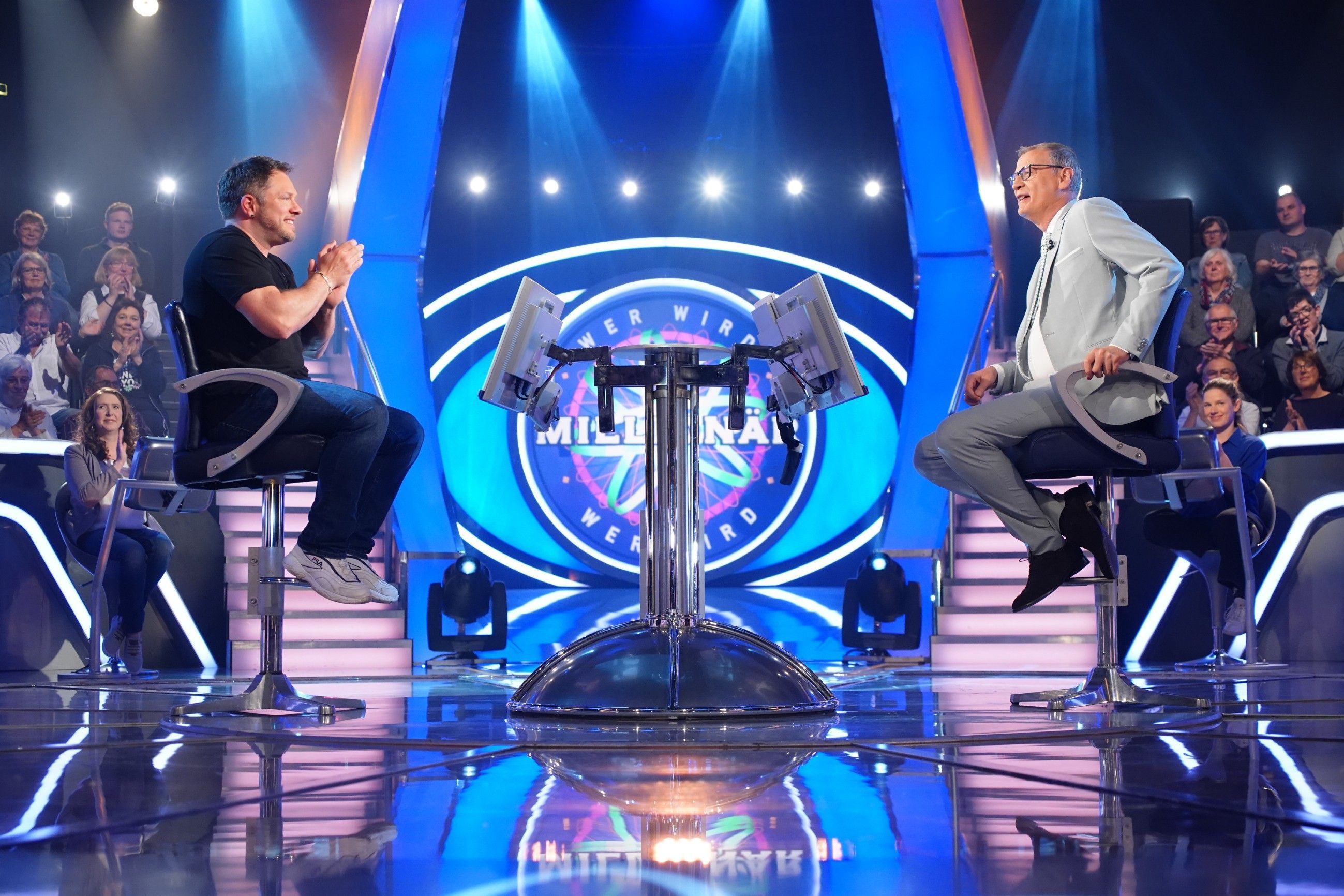 Dieses Symbolfoto zeigt RTL-Moderator Günther Jauch (r.) bei der Sendung „Wer wird Millionär?“ vom 8. August 2022. Jauch sitzt auf einem Hocker und schaut den Kandidaten an.