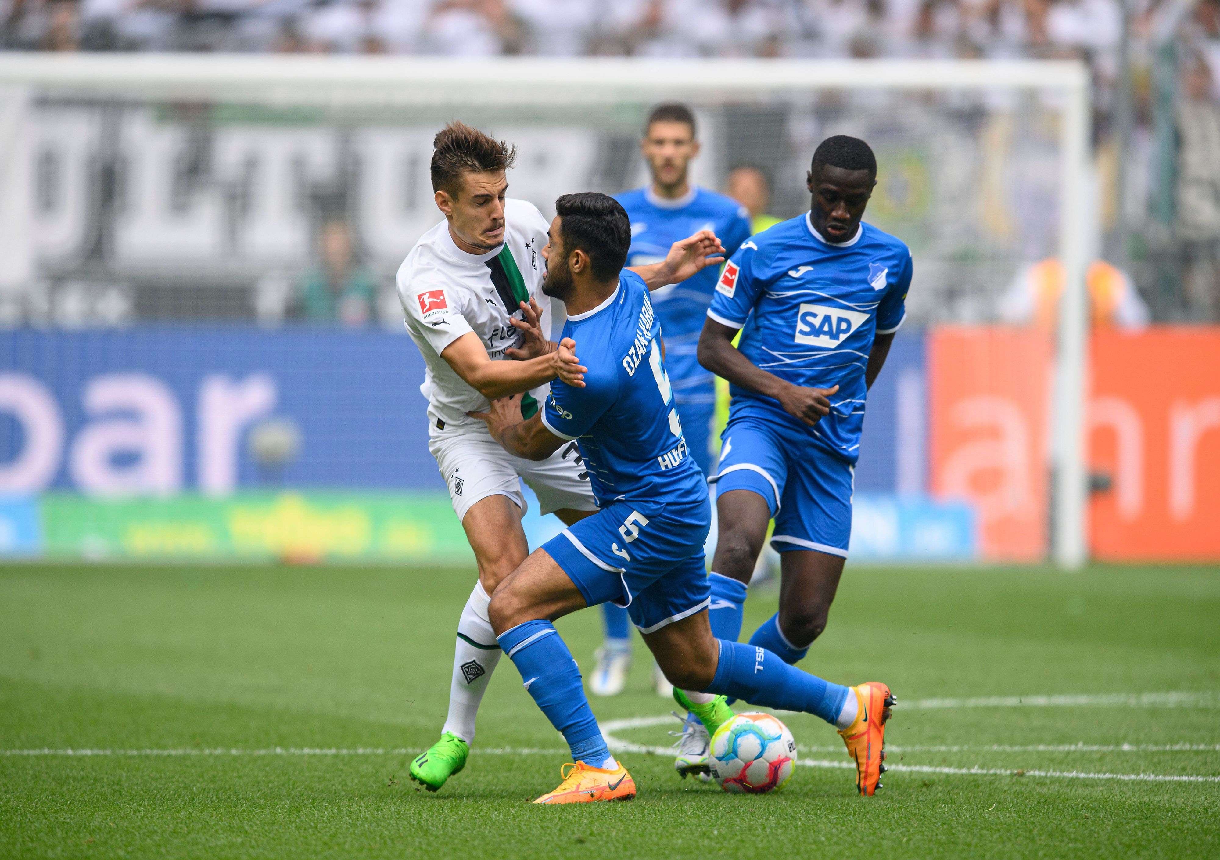 Gladbach-Profi Florian Neuhaus (l.) hat beim Bundesliga-Auftaktsieg im Borussia-Park gegen die TSG Hoffenheim (6. August 2022) einiges in den Zweikämpfen einstecken müssen und ist vor dem Schalke-Duell angeschlagen. Neuhaus wird vom Gegenspieler zur Seite gedrückt.