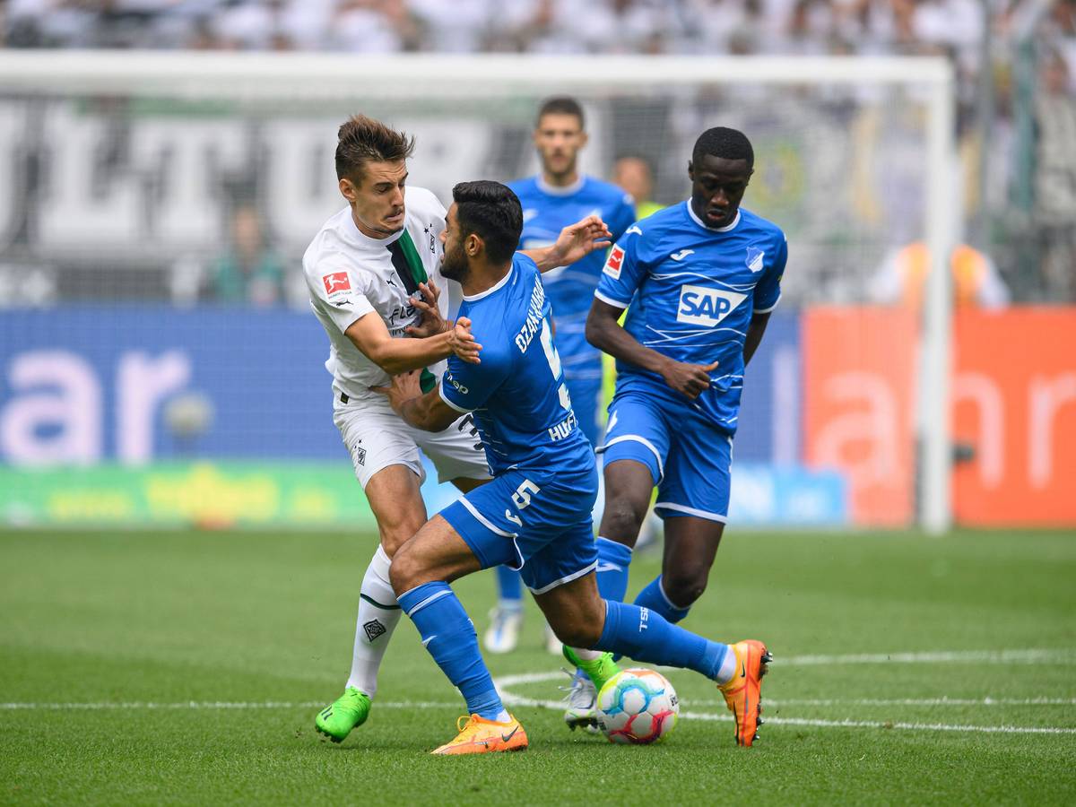 Gladbach-Profi Florian Neuhaus (l.) hat beim Bundesliga-Auftaktsieg im Borussia-Park gegen die TSG Hoffenheim (6. August 2022) einiges in den Zweikämpfen einstecken müssen und ist vor dem Schalke-Duell angeschlagen. Neuhaus wird vom Gegenspieler zur Seite gedrückt.