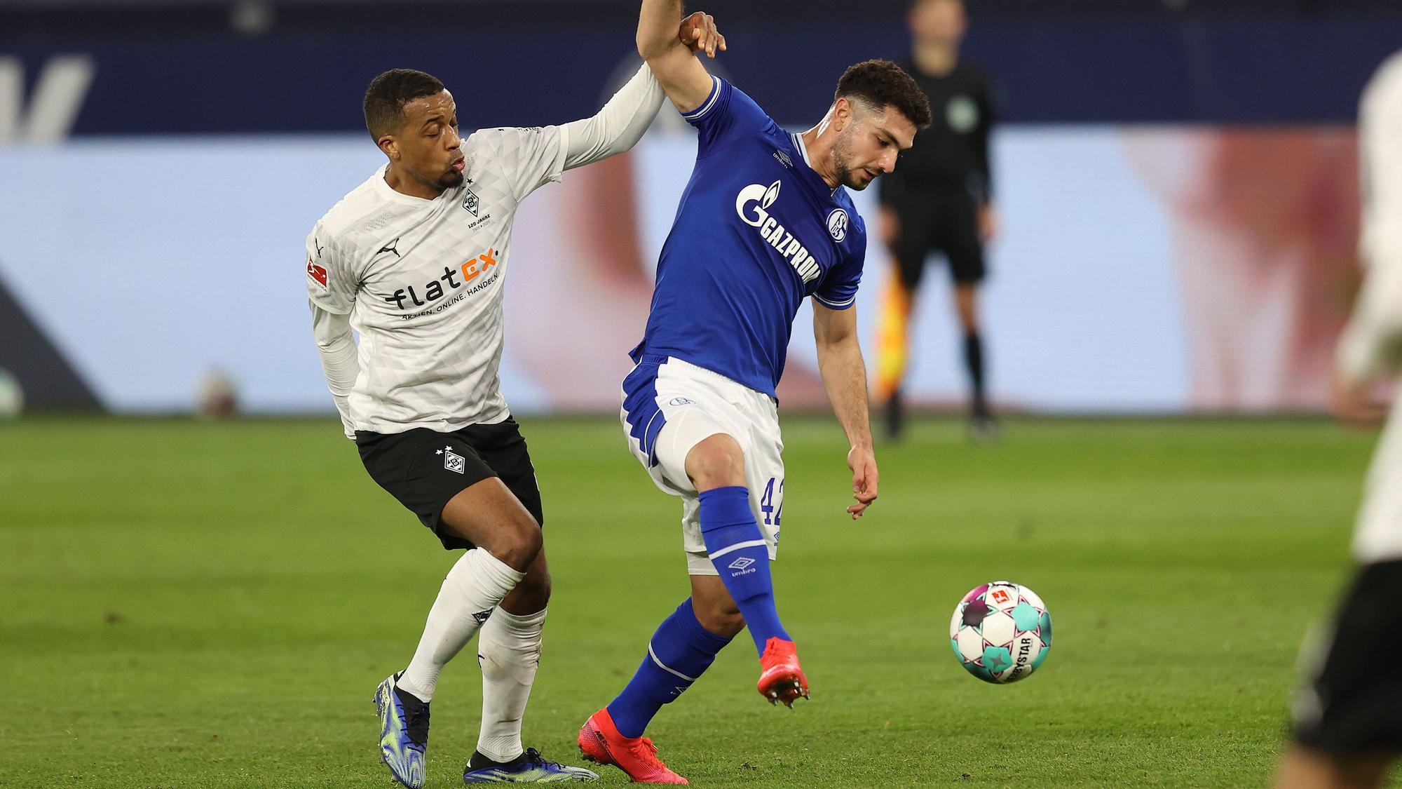 Borussia Mönchengladbach tritt am Samstag (13. August 2022) am 2. Bundesliga-Spieltag beim FC Schalke 04 an. Das Foto zeigt Gladbachs Alassane Plea (l.) und Schalkes Kerim Calhanoglu (r.) im vergangenen Duell am 20. März 2021.