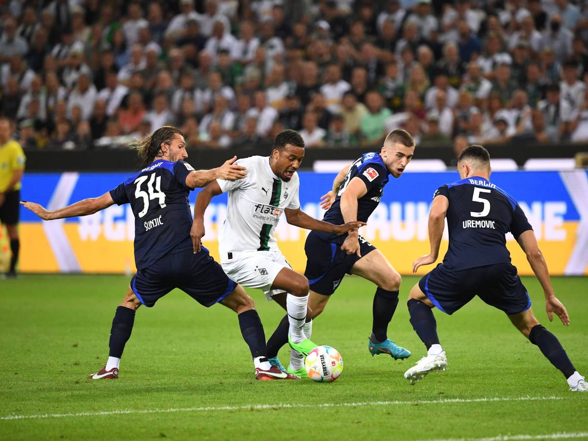 Gladbachs Alassane Plea (weiß, Mitte) im Zweikampf mit Berlins Ivan Sunjic (Nr. 34), Jonjoe Kenny (blau, Mitte) und Filip Uremovic (Nr. 5). Plea erzielte am 19. August 2022 die 1:0-Führung für Borussia Mönchengladbach gegen Hertha BSC per Elfmeter.