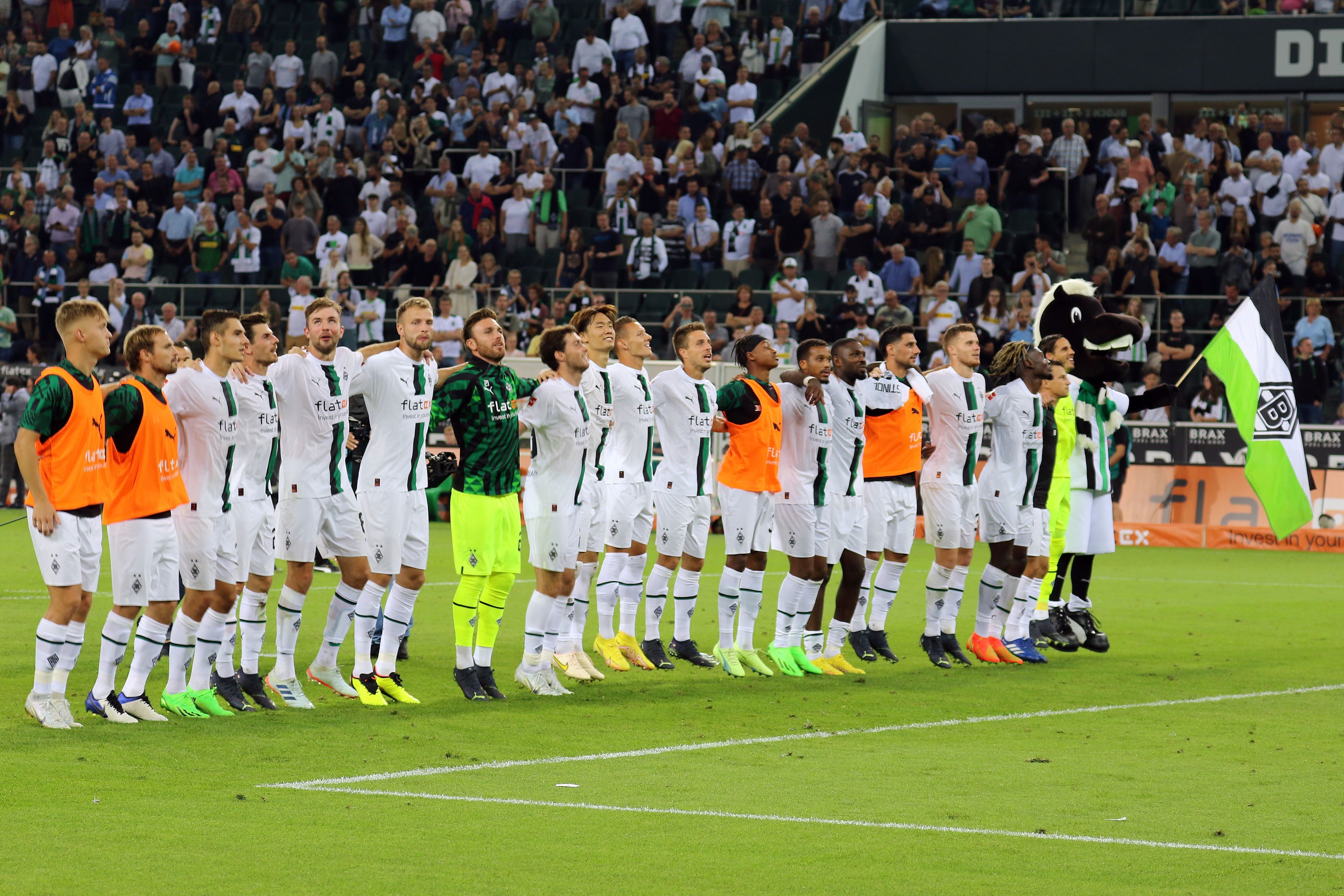 Die Spieler von Borussia Mönchengladbach feiern am Freitag (19. August 2022) gemeinsam mit den Fans in der Nordkurve den Heimsieg gegen Hertha BSC. Maskottchen Jünter ist auch dabei.